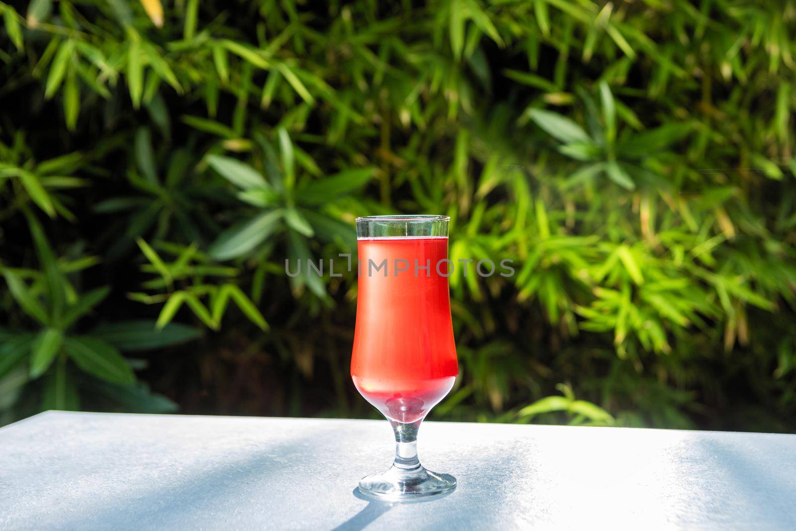 Red juice cocktail glass with green background