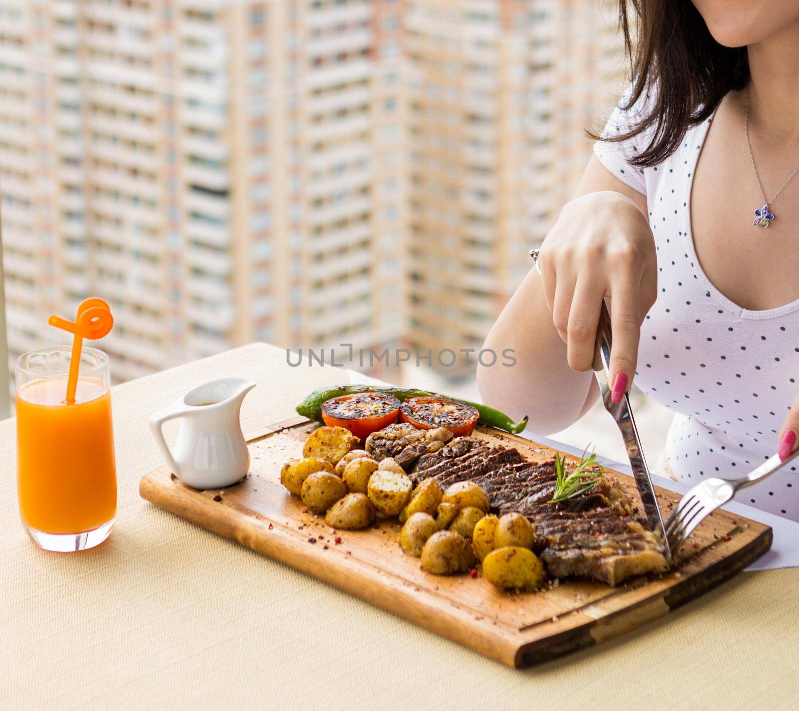 Woman eating tasty steak potato, vegetable on the wood plate by ferhad