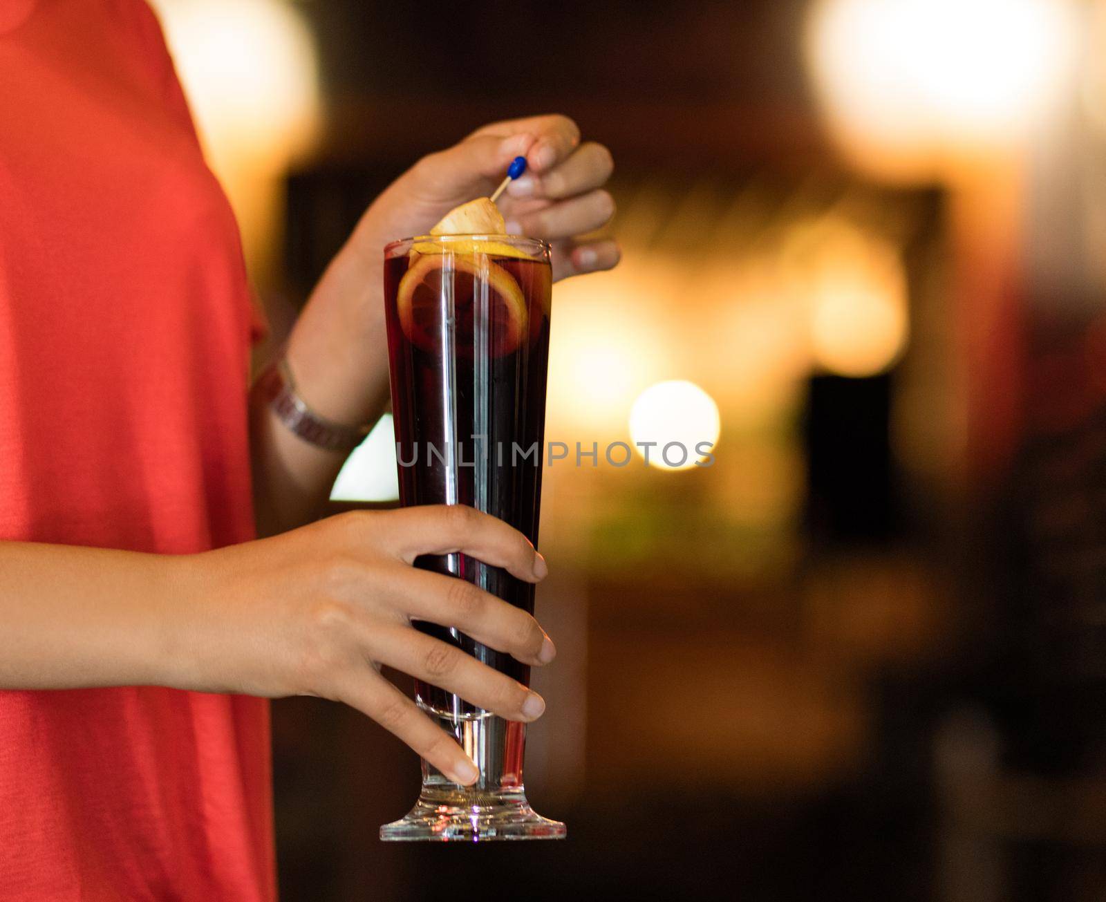 Woman holding glass of lemon cocktail isolated on a bokeh background by ferhad
