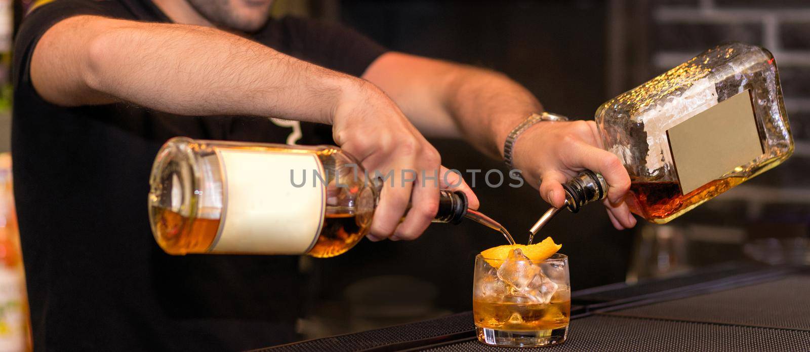 Barman making a new alcoholic cocktail, pouring drinks into a glass