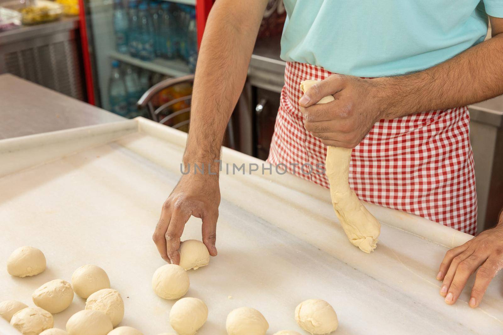 Restaurant male worker carving the dough, table and hands in flour. Natural restaurant cooking.