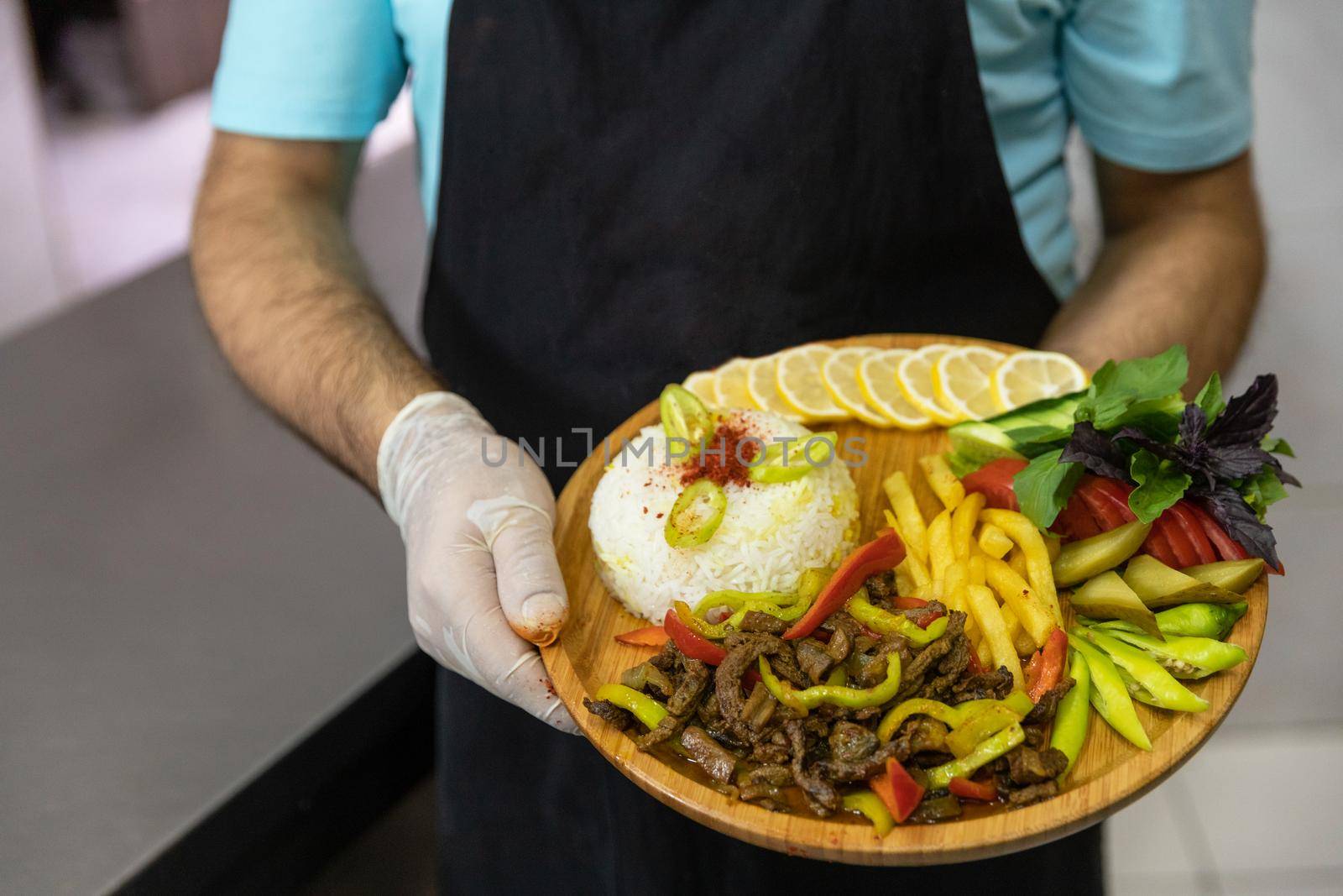 Restaurant chef holding tasty meat meal with salad, vegetables on the wooden plate