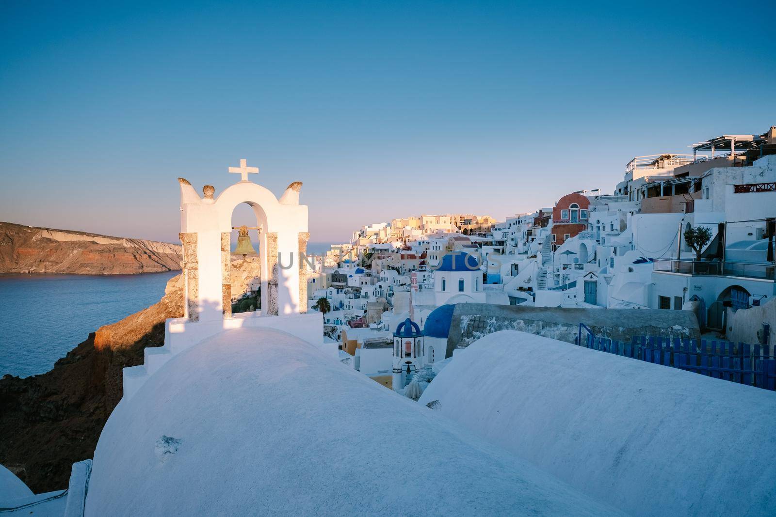 Sunset at the Island Of Santorini Greece, beautiful whitewashed village Oia with church and windmill during sunset by fokkebok