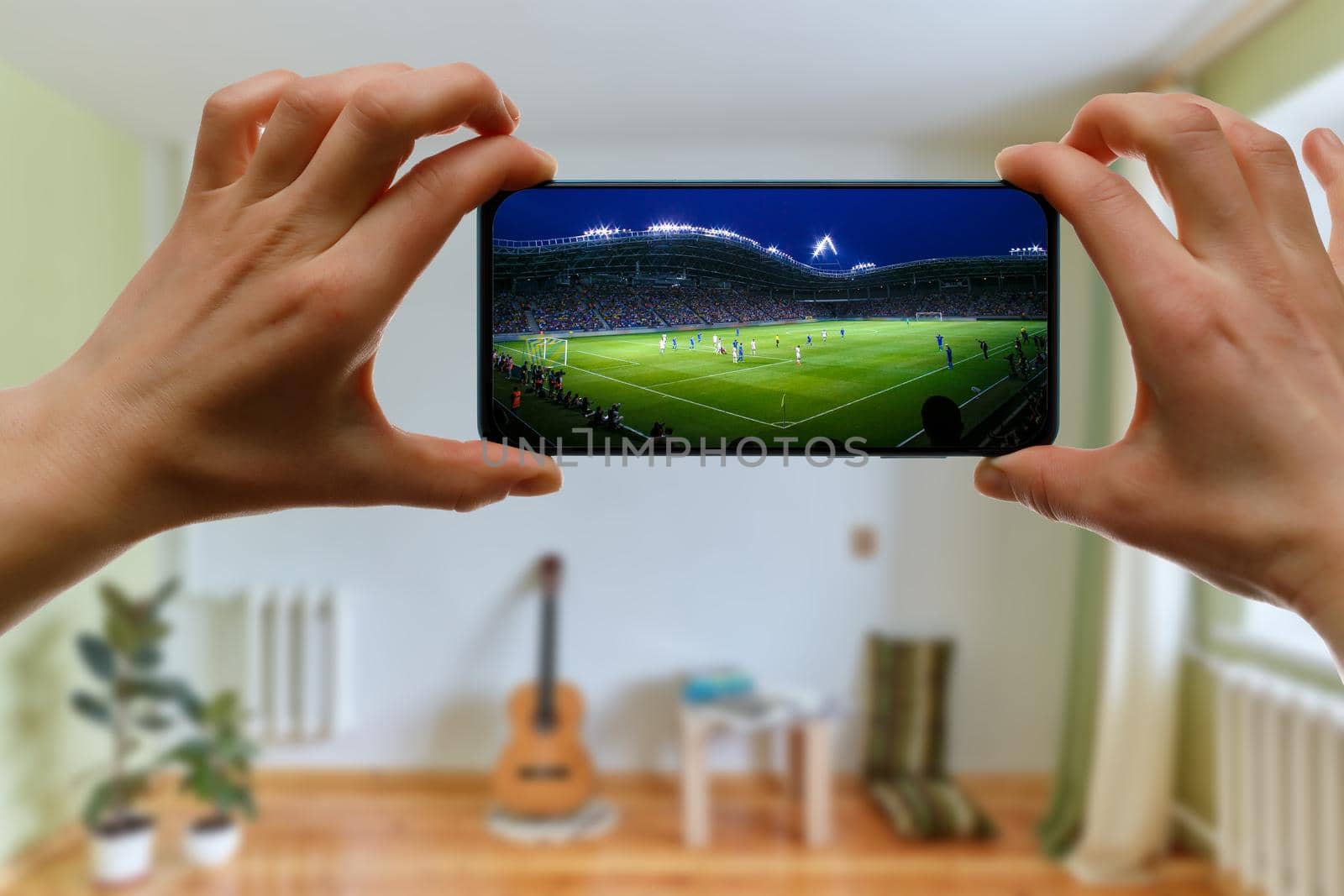 Watching football game at home via smartphone. Broadcasting soccer from the stadium. by 9parusnikov