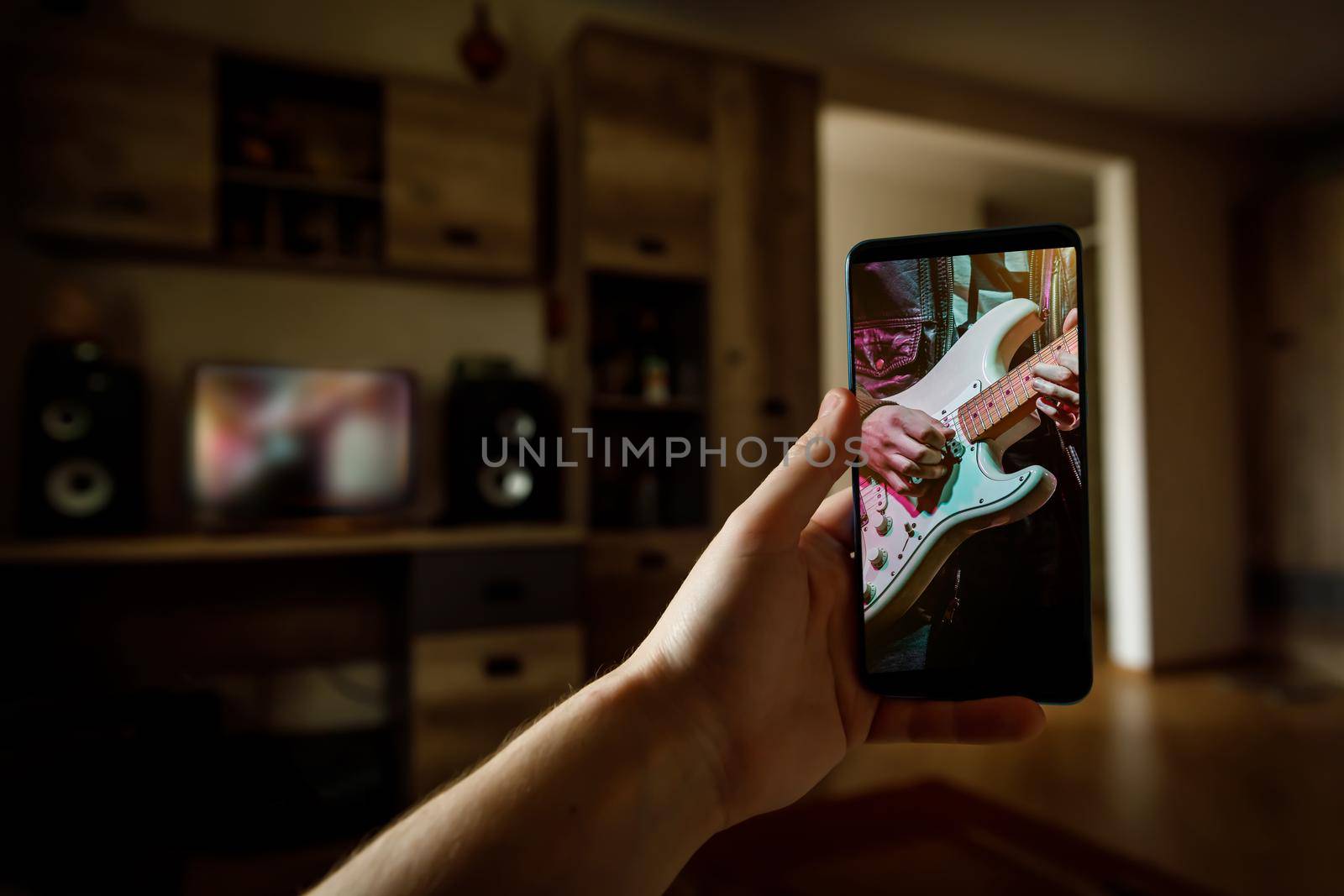 Online music lesson via mobile phone at home. Guitar teacher hands on screen.