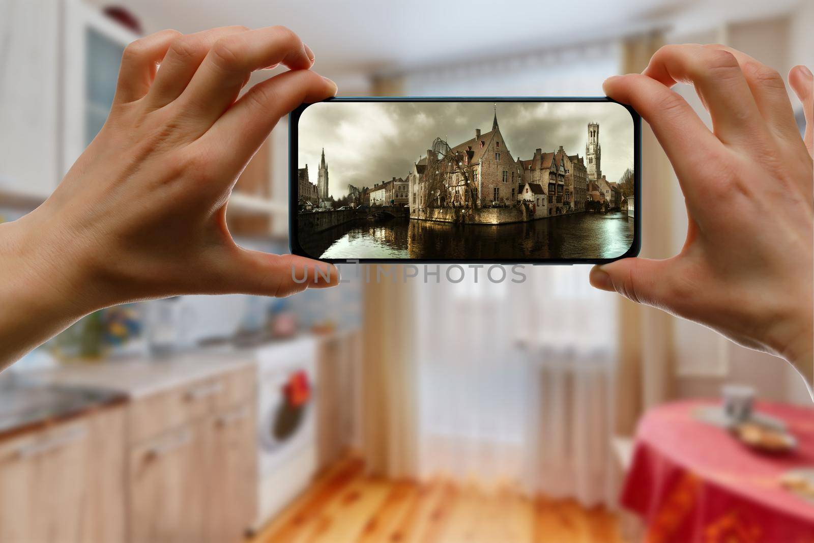 Looking at medieval city Brugge on a mobile phone screen from home. Online tourism concept