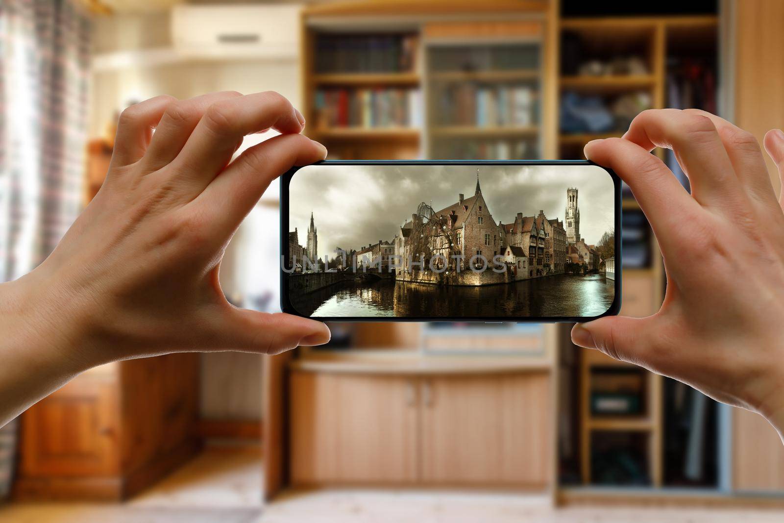 Looking at medieval city Brugge on a mobile phone screen from home. by 9parusnikov