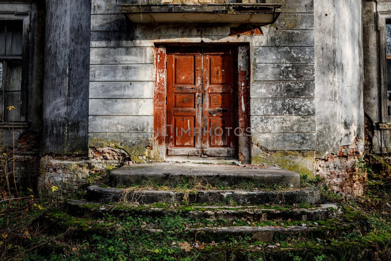 Porch of an old palace with a stone staircase and a red door