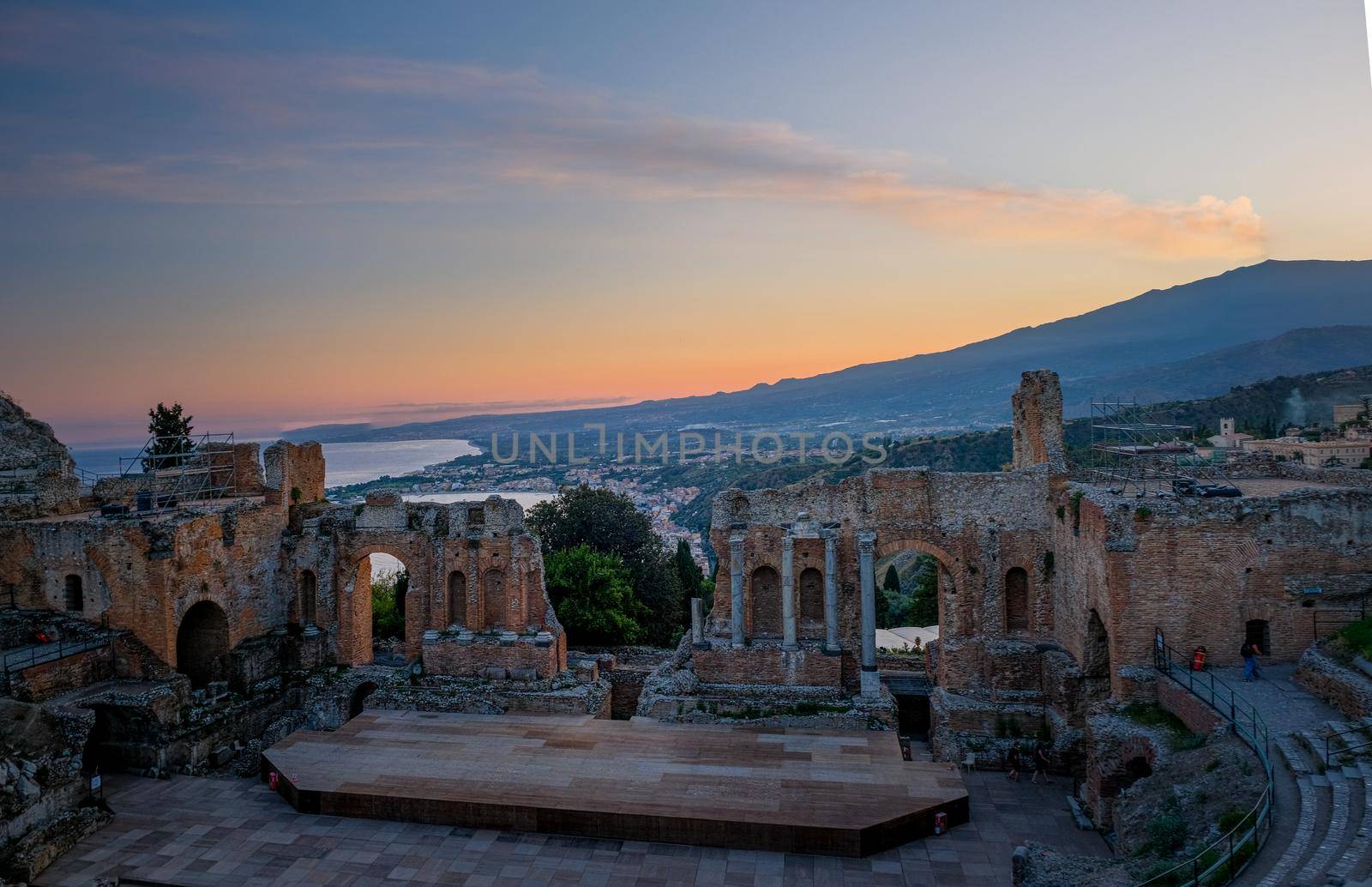 Ruins of Ancient Greek theatre in Taormina on background of Etna Volcano, Italy. Taormina located in Metropolitan City of Messina, on east coast of island of Sicily. by fokkebok