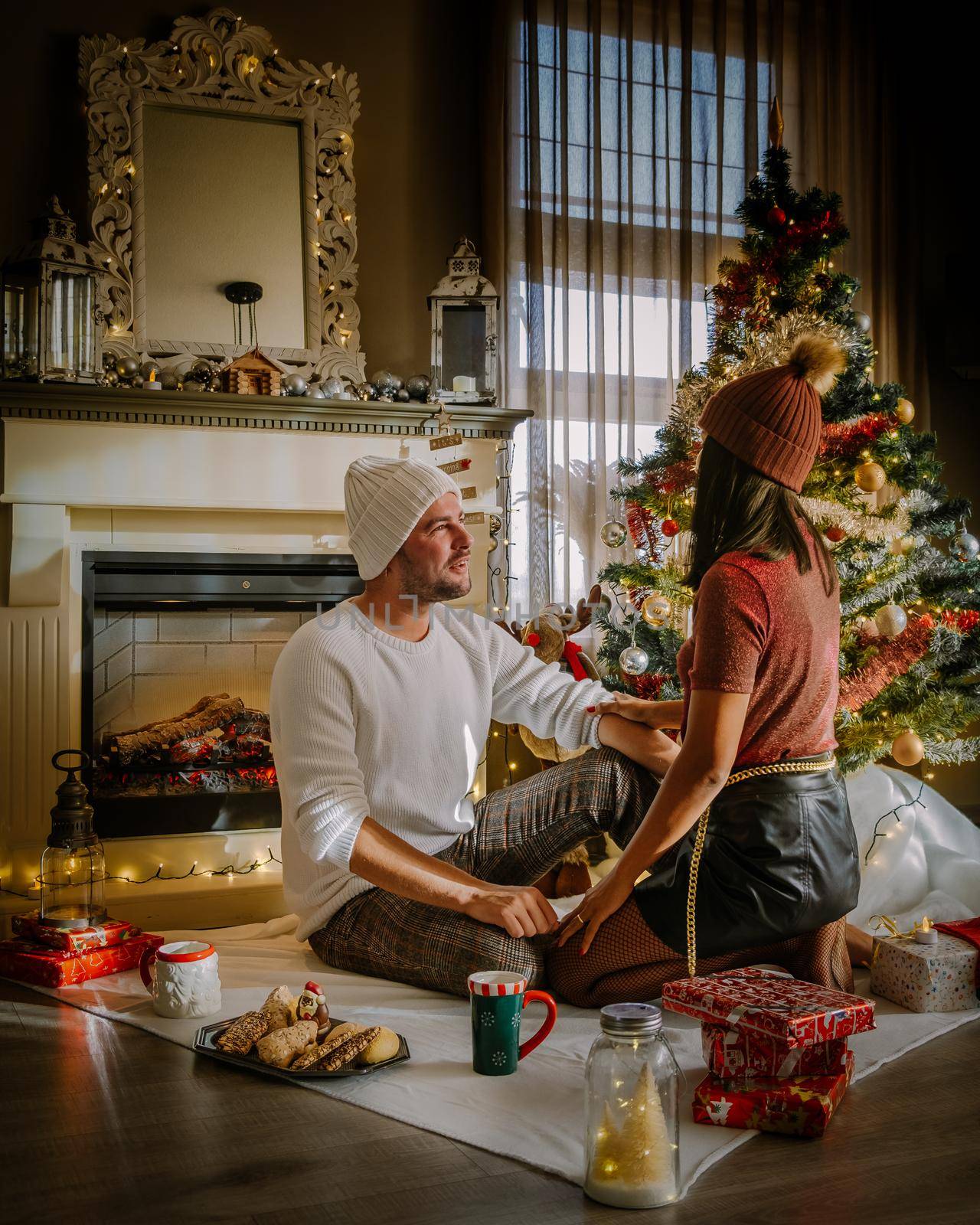 Family sitting on a floor. Couple near christmas tree, Christmas couple with present by fokkebok