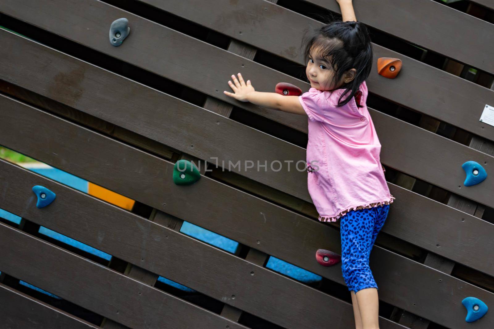 Pretty asian little girls while climbing in a playground