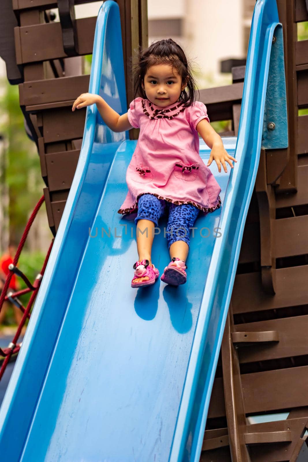 Pretty asian little girls while sliding in a playground