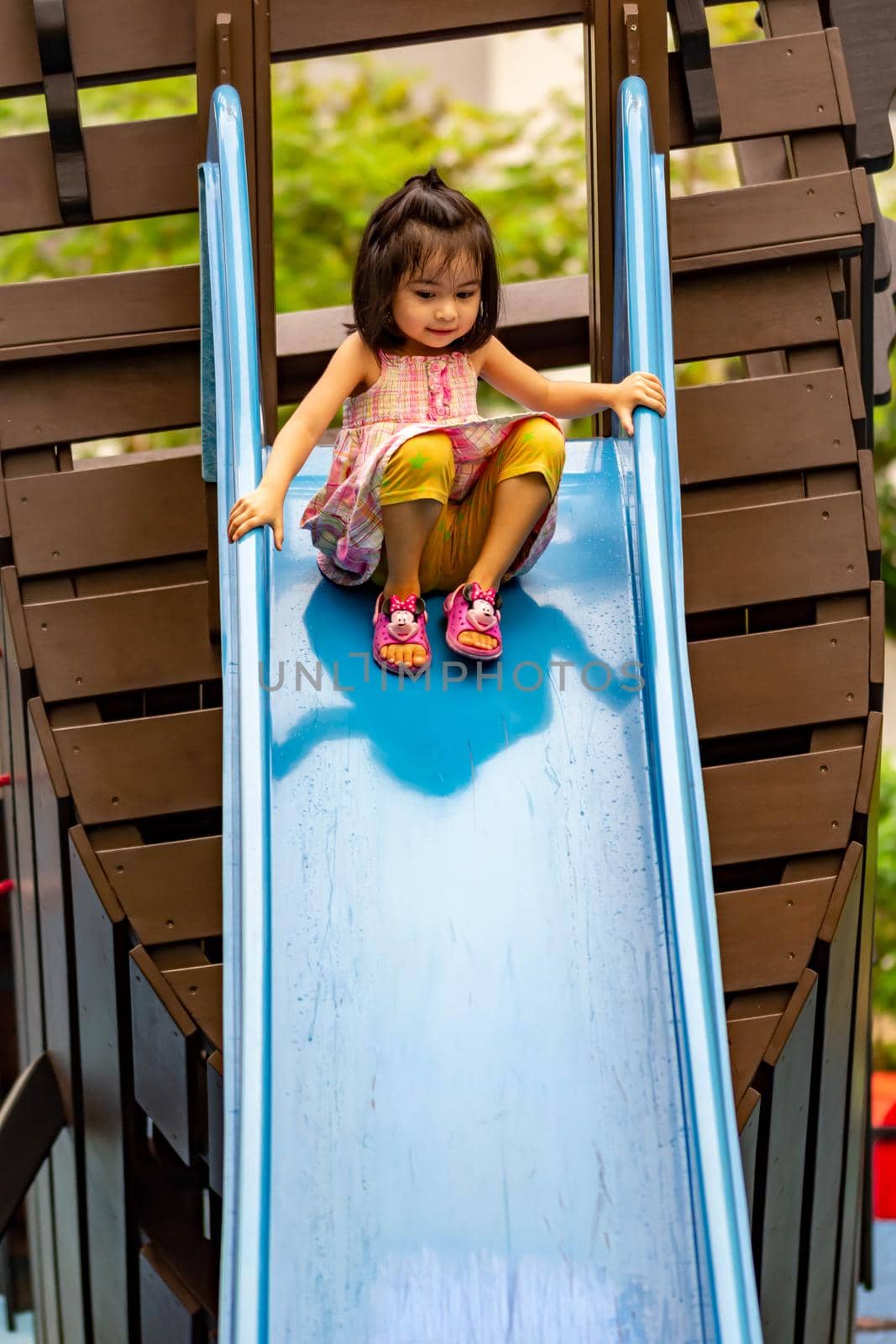 Pretty asian little girls while sliding in a playground