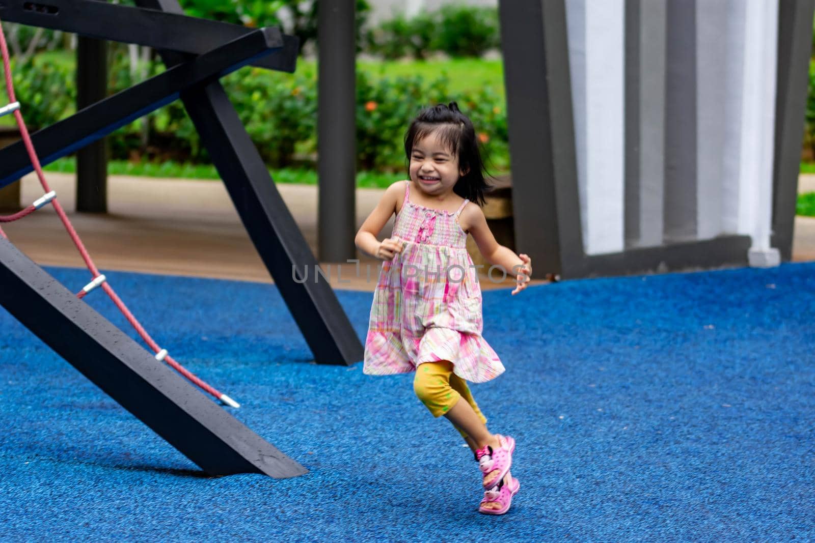 Cute little asian kid girl while running and enjoying on a playground