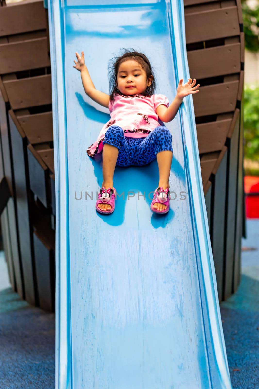 Pretty asian little girls while sliding in a playground