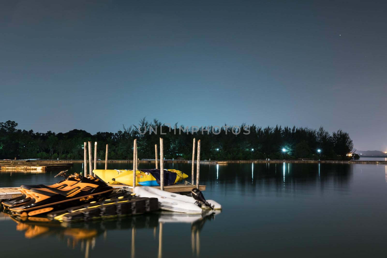 Landscape view of bridge, lake and nature with a bridge and some jetski. Bright night sky with stars and smooth light reflecting on waters somewhere in Asia