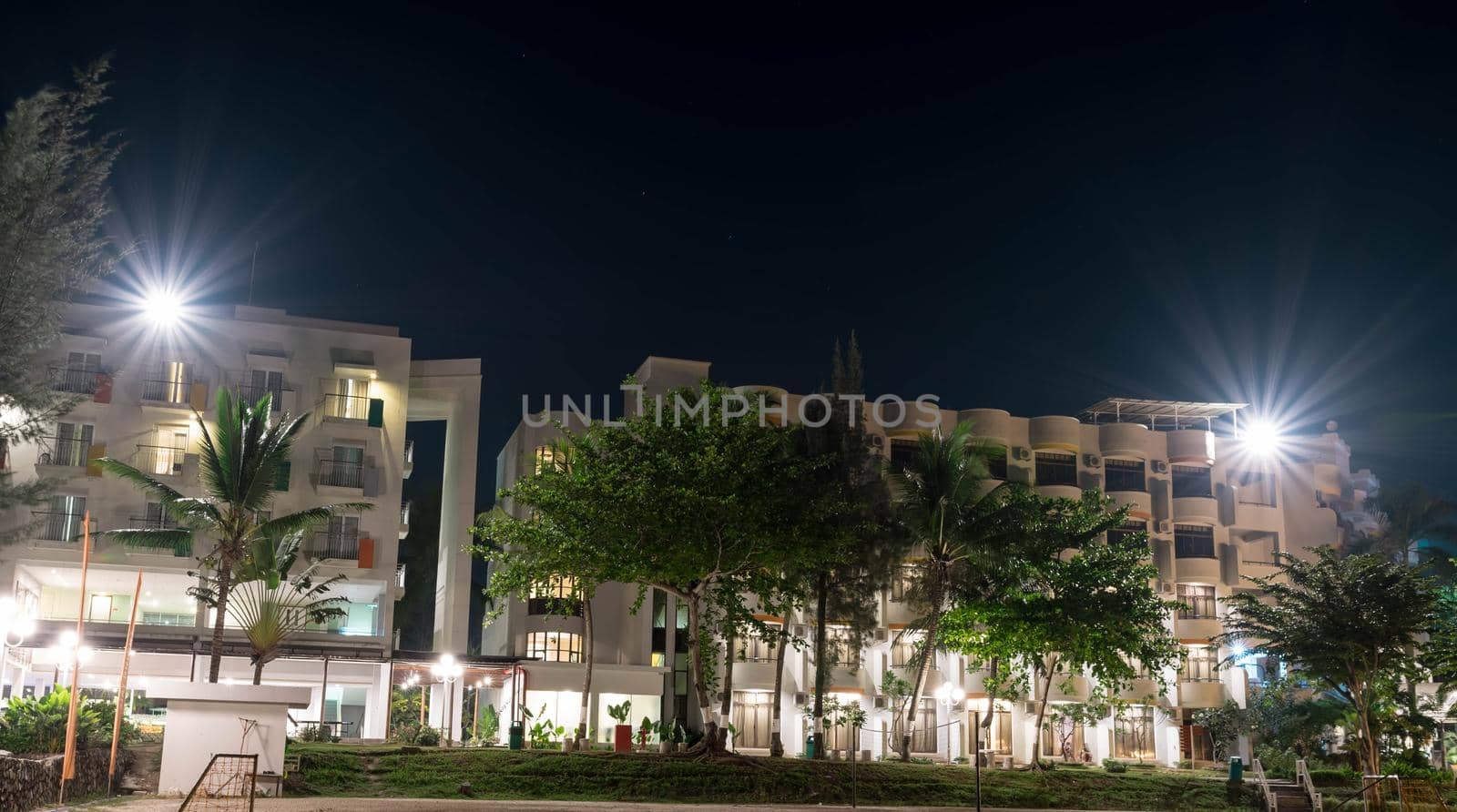 Hotel in a beach resort during night with bright lights and trees with clear sky and stars somewhere in Asia