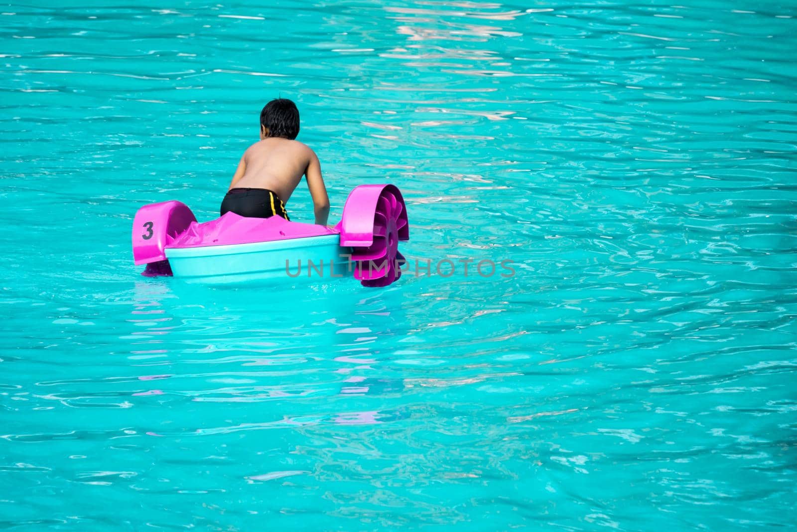 Child playing a water pedal boat in a swimming pools