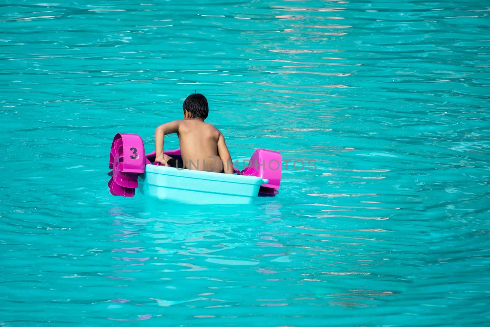 Child playing a water pedal boat in a swimming pools