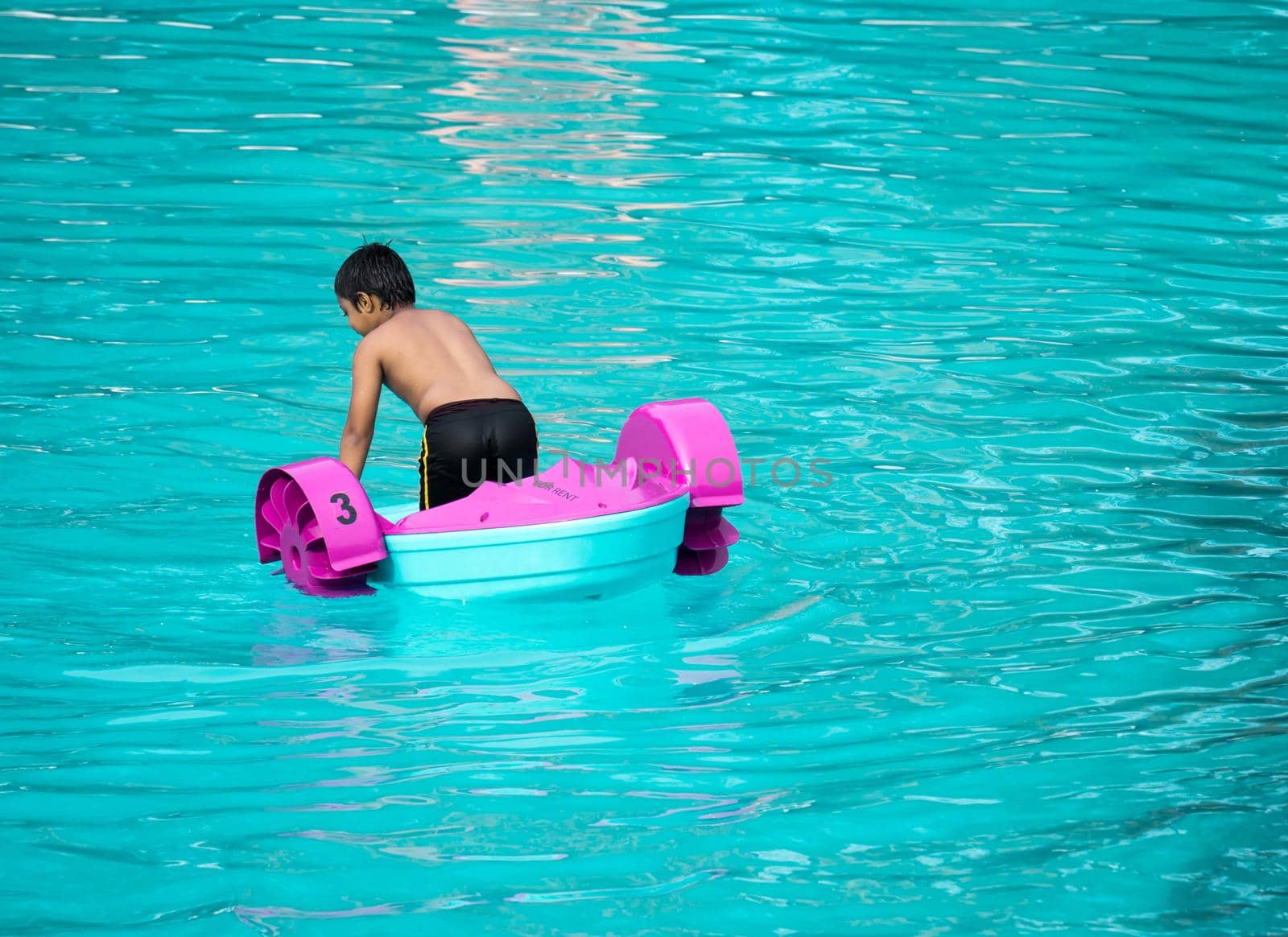 Child playing a water pedal boat in a swimming pools