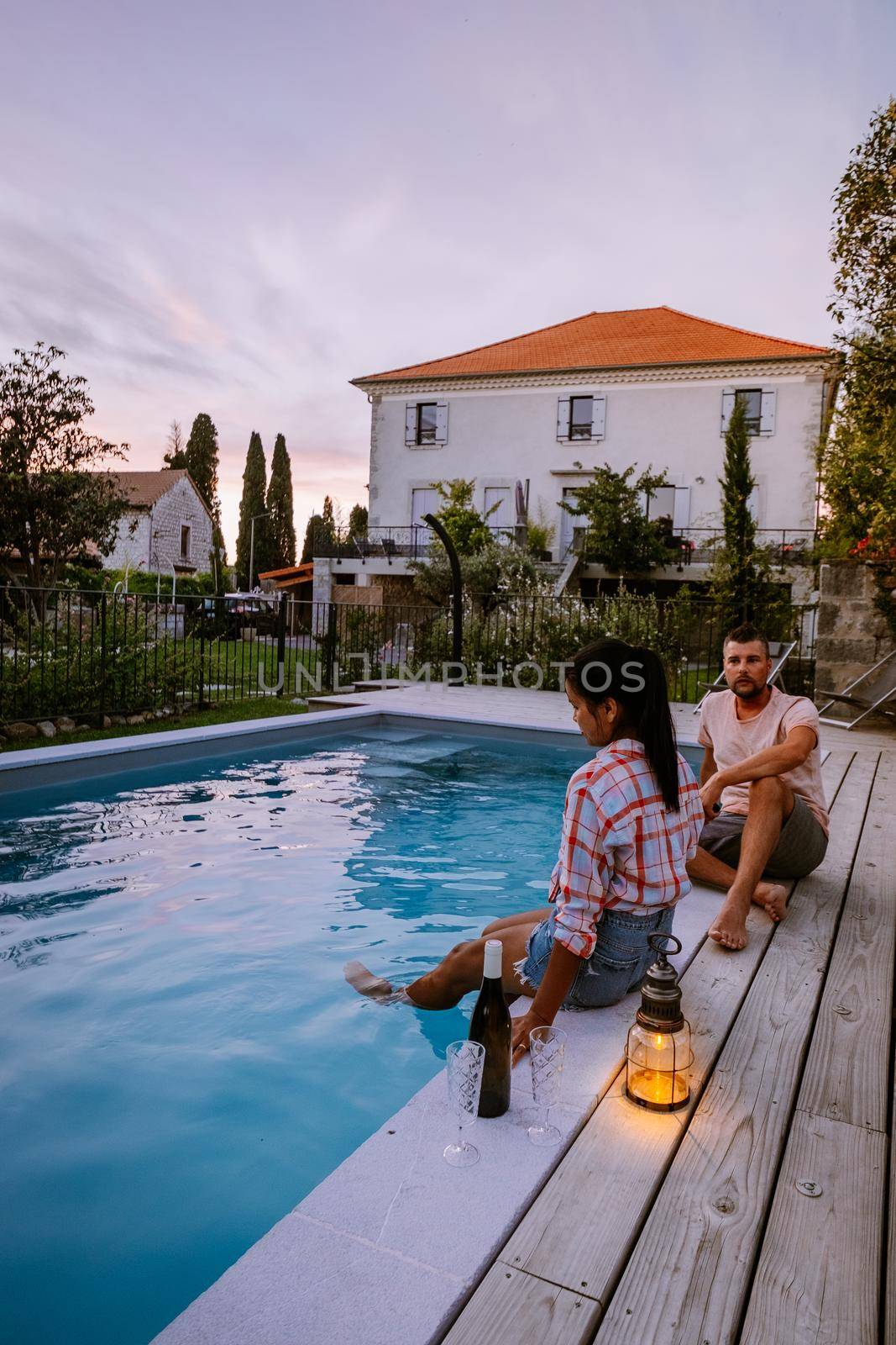 French vacation home with wooden deck and swimming pool in the Ardeche France. Couple relaxing by the pool with wooden deck during luxury vacation at an holiday home in South of France by fokkebok