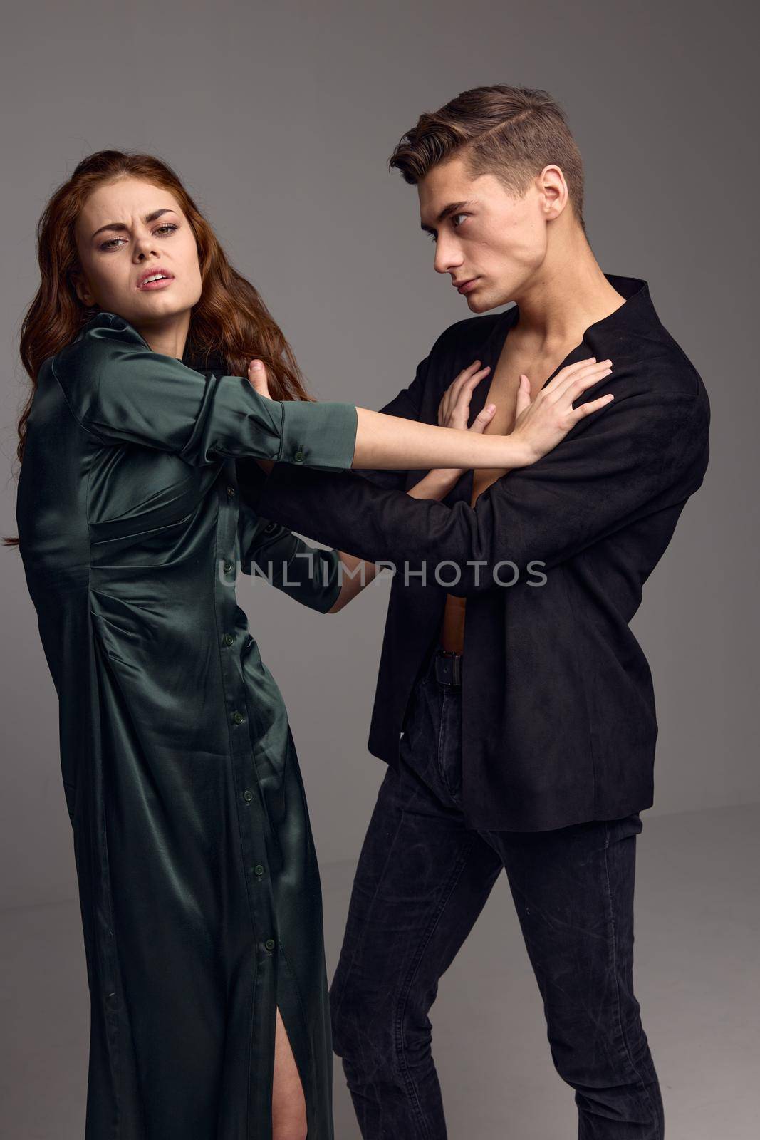 Domestic violence aggressive man holding a woman by the hair on a gray background. High quality photo