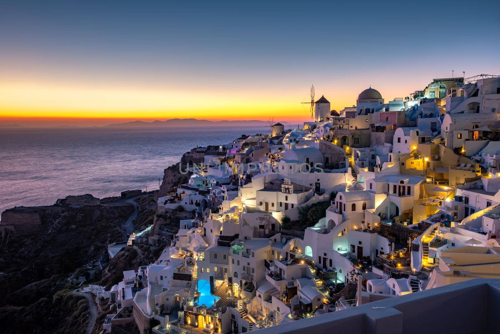 Sunset at the Island Of Santorini Greece, beautiful whitewashed village Oia with church and windmill during sunset, streets of Oia Santorini during summer vacation at the Greek Island