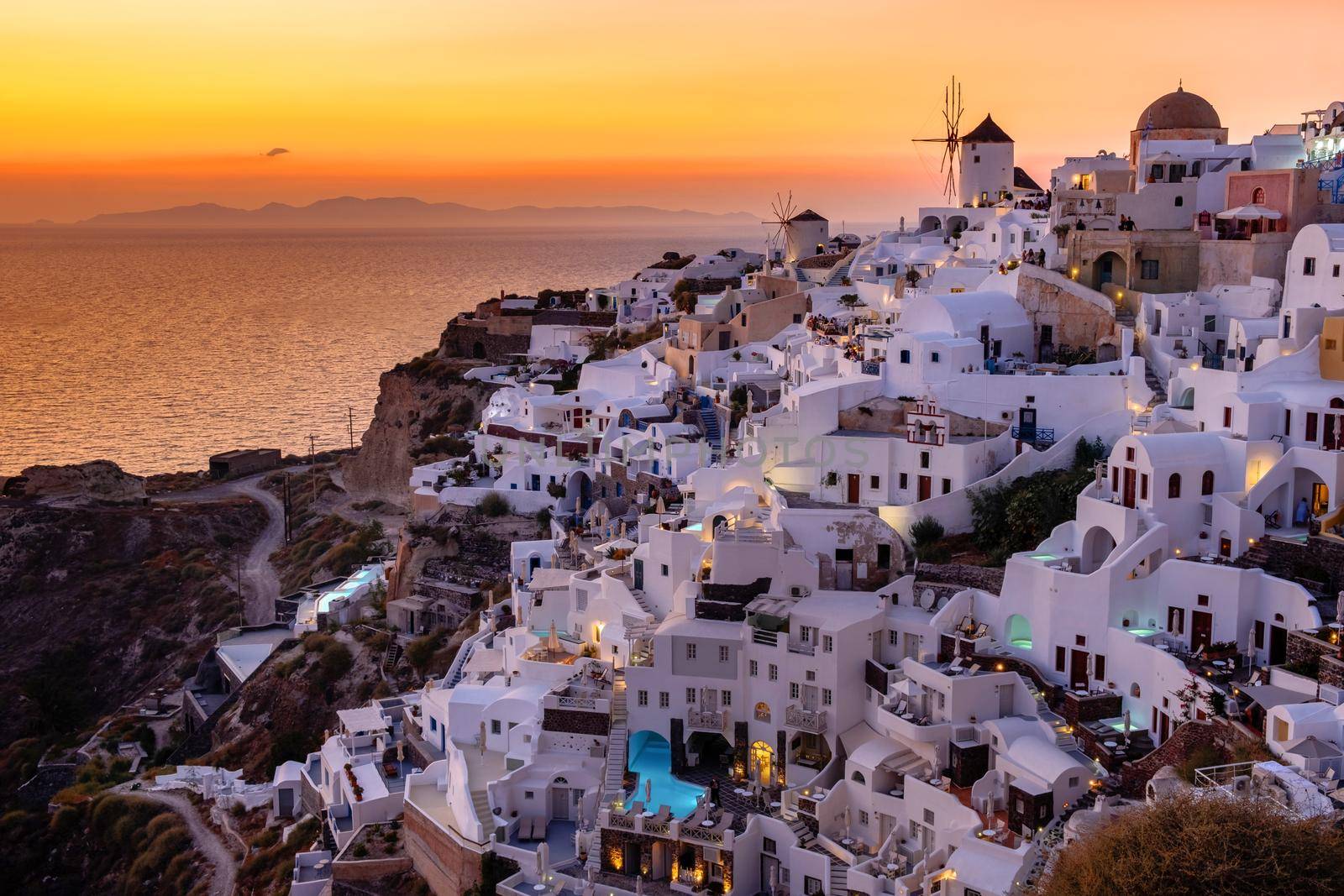 Sunset at the Island Of Santorini Greece, beautiful whitewashed village Oia with church and windmill during sunset, streets of Oia Santorini during summer vacation at the Greek Island