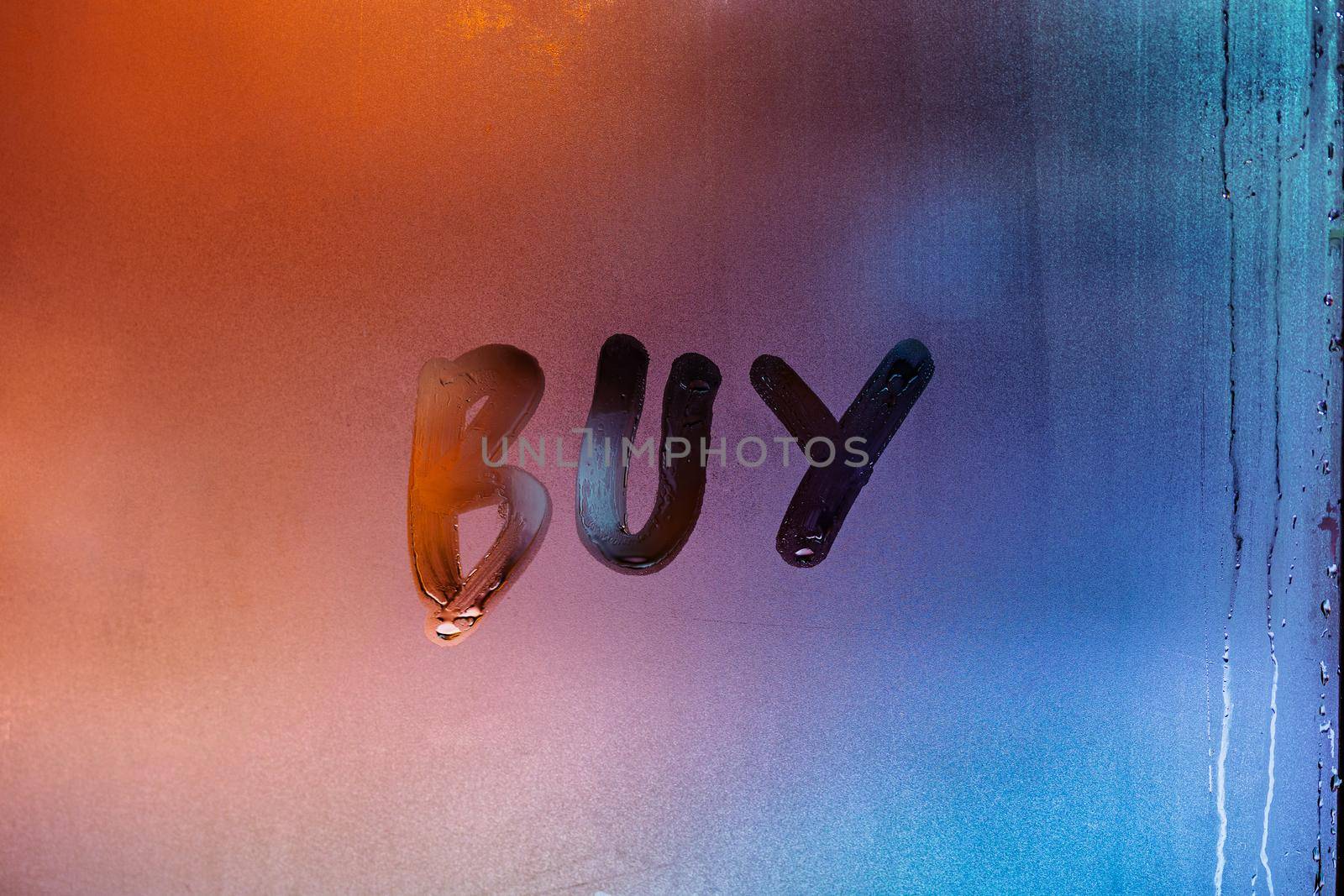 word buy handwritten on night wet window glass surface - close-up with selective focus