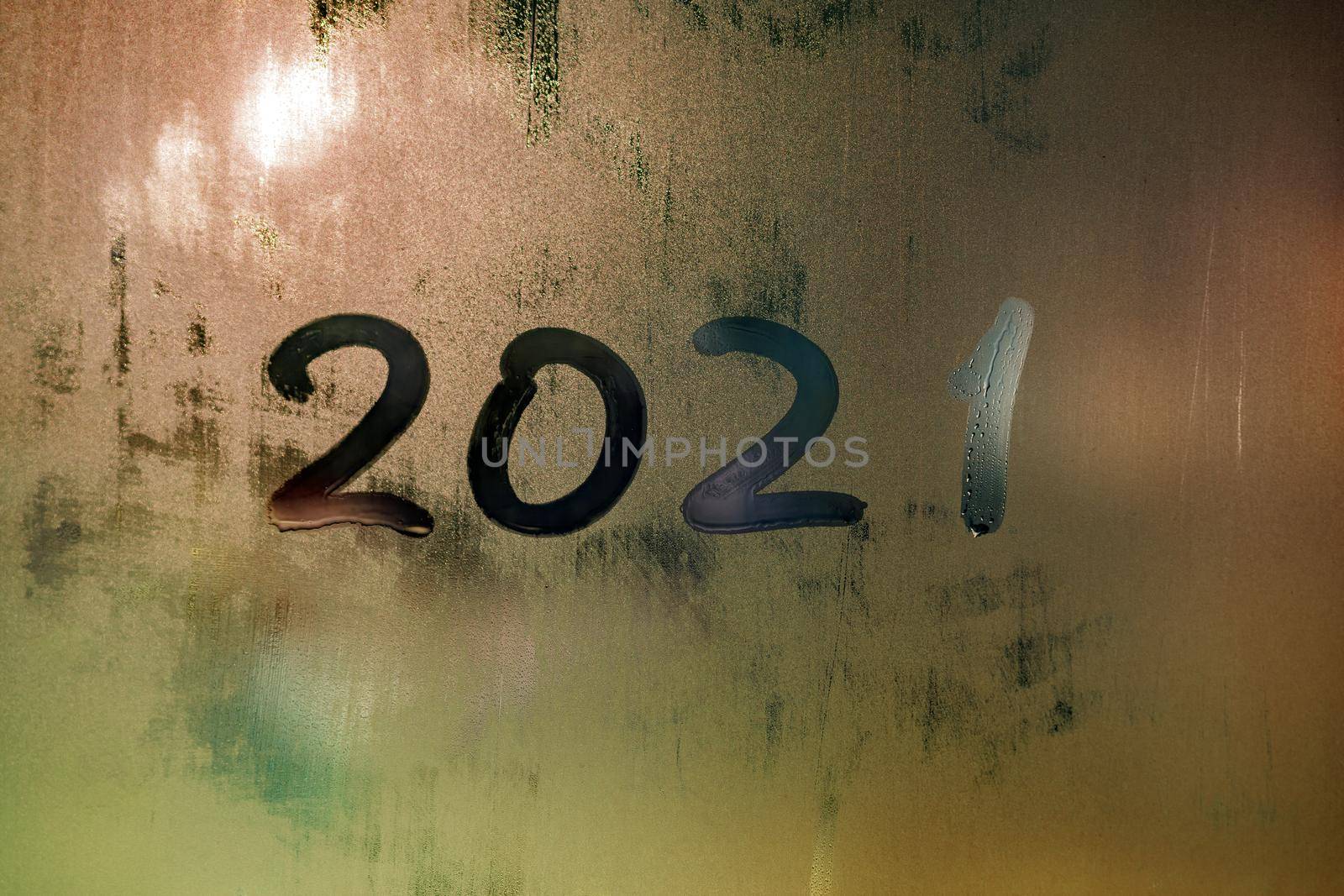 digit 2021 handwritten on wet night window glass surface, close-up with selective focus