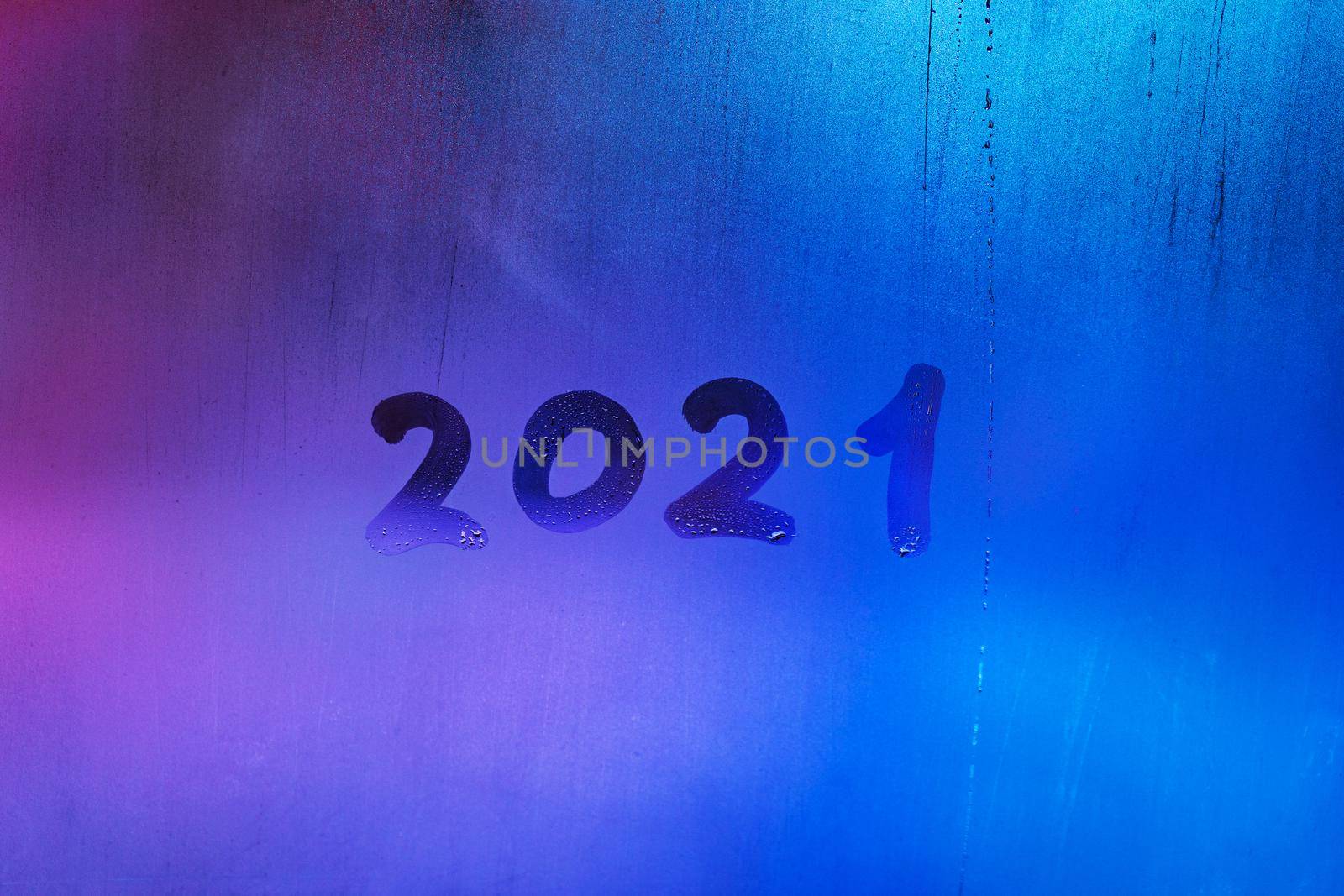 digit 2021 handwritten on wet night window glass surface, close-up with selective focus