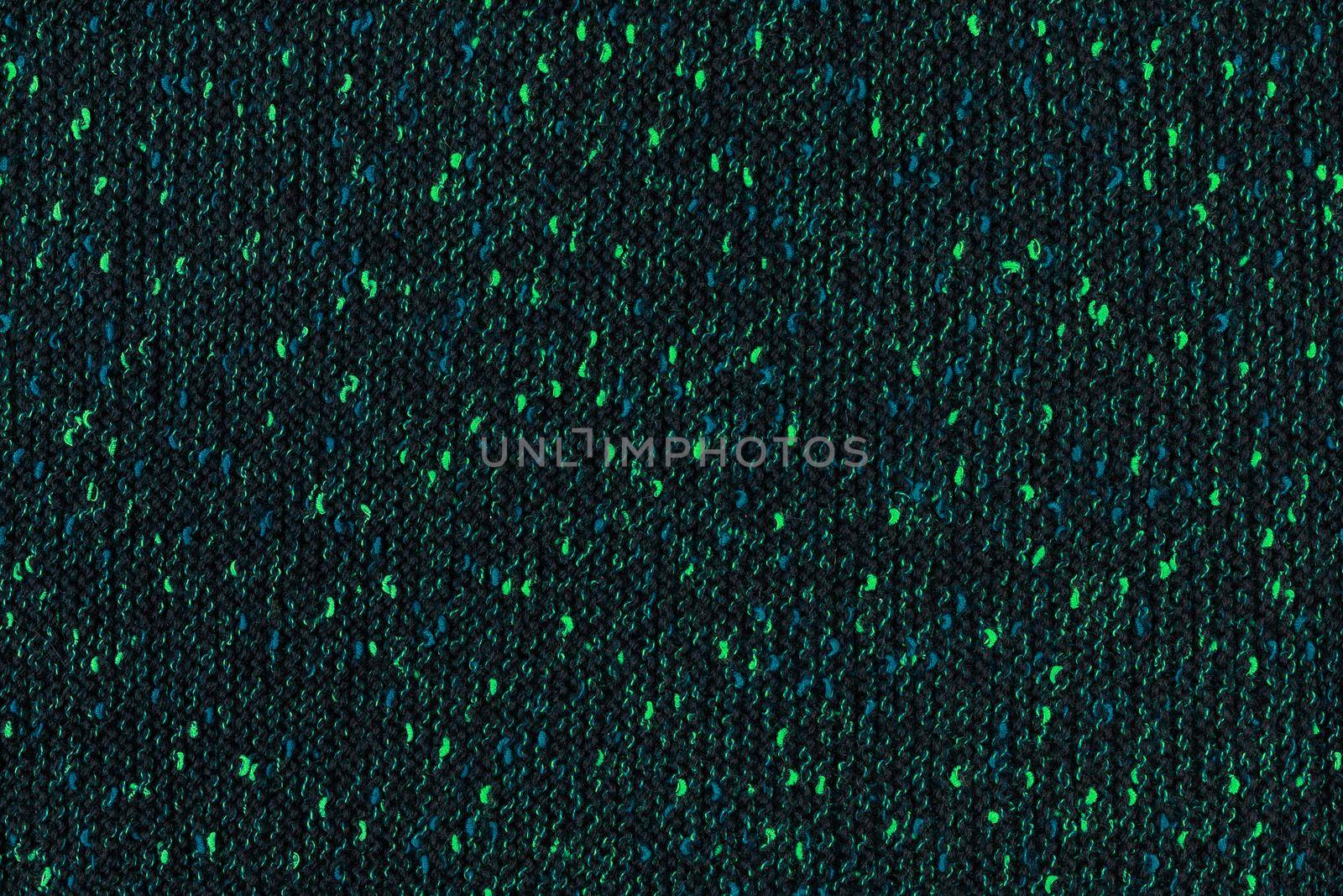 black melange manually knitted fabric with emerald green and blue blotches - seamless texture and flat background.