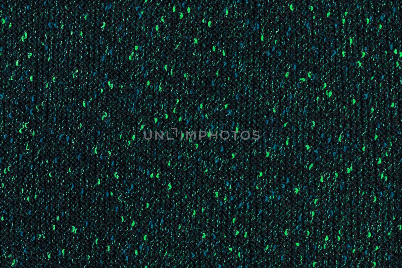 black melange manually knitted fabric with emerald green and blue blotches - seamless texture and flat background.