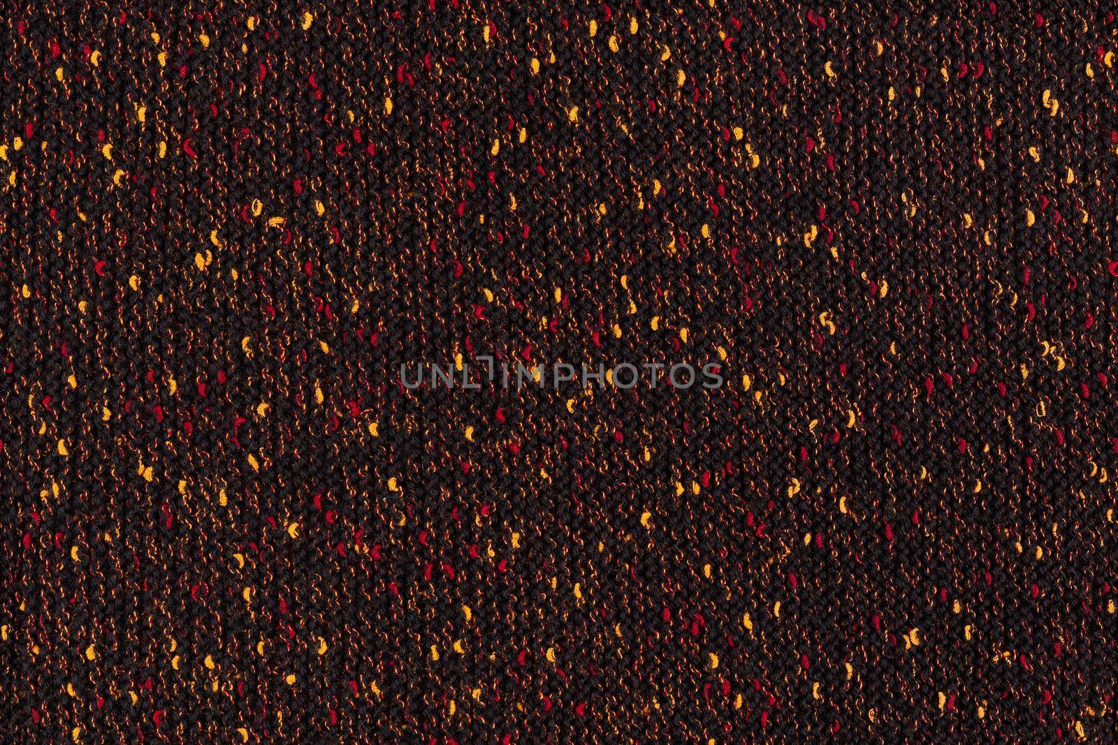 black melange manually knitted fabric with red and yellow blotches - seamless texture and flat background.