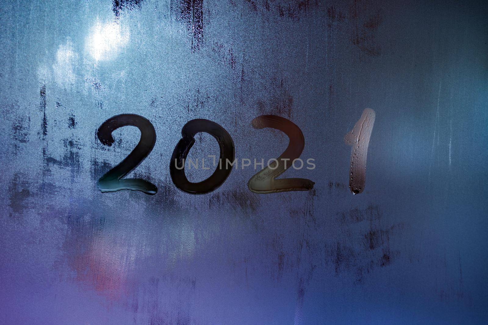 digit 2021 handwritten on wet night window glass surface, close-up with selective focus