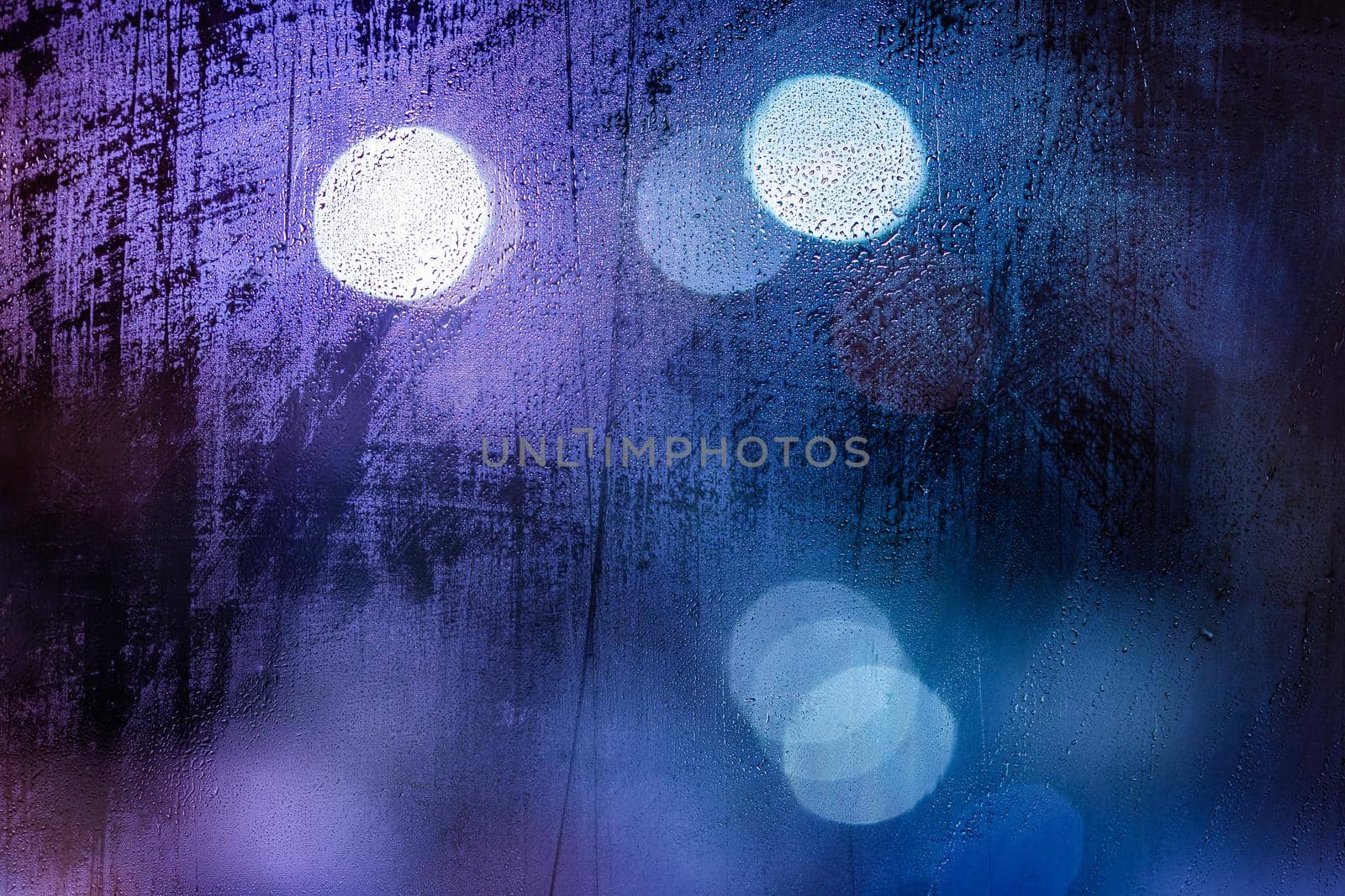 an abstract background of night wet window glass with smudges in blue tone gamma.