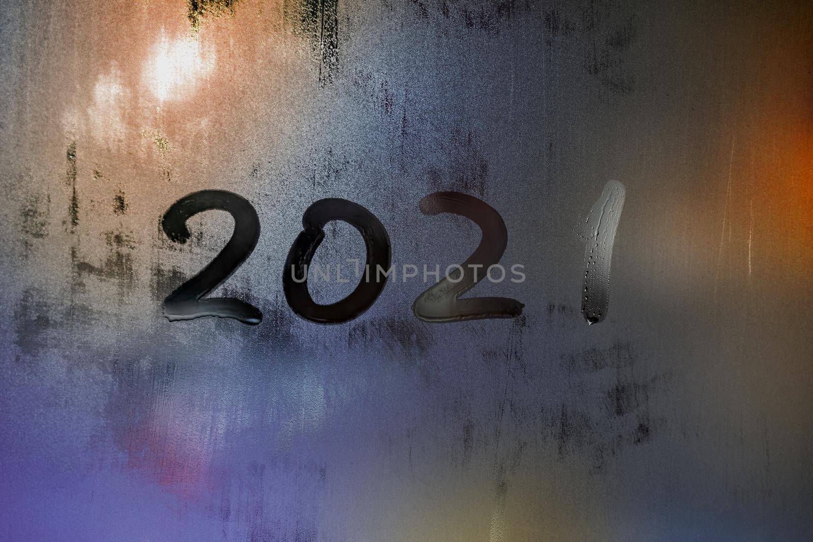 digit 2021 handwritten on wet night window glass surface, close-up with selective focus