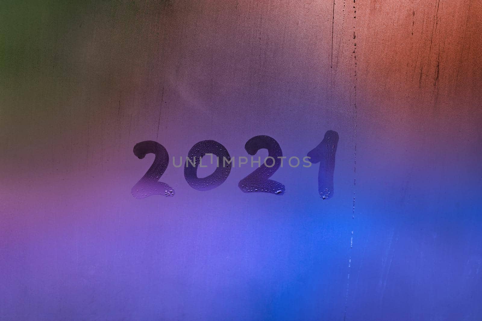 digit 2021 handwritten on wet night window glass surface, close-up with selective focus