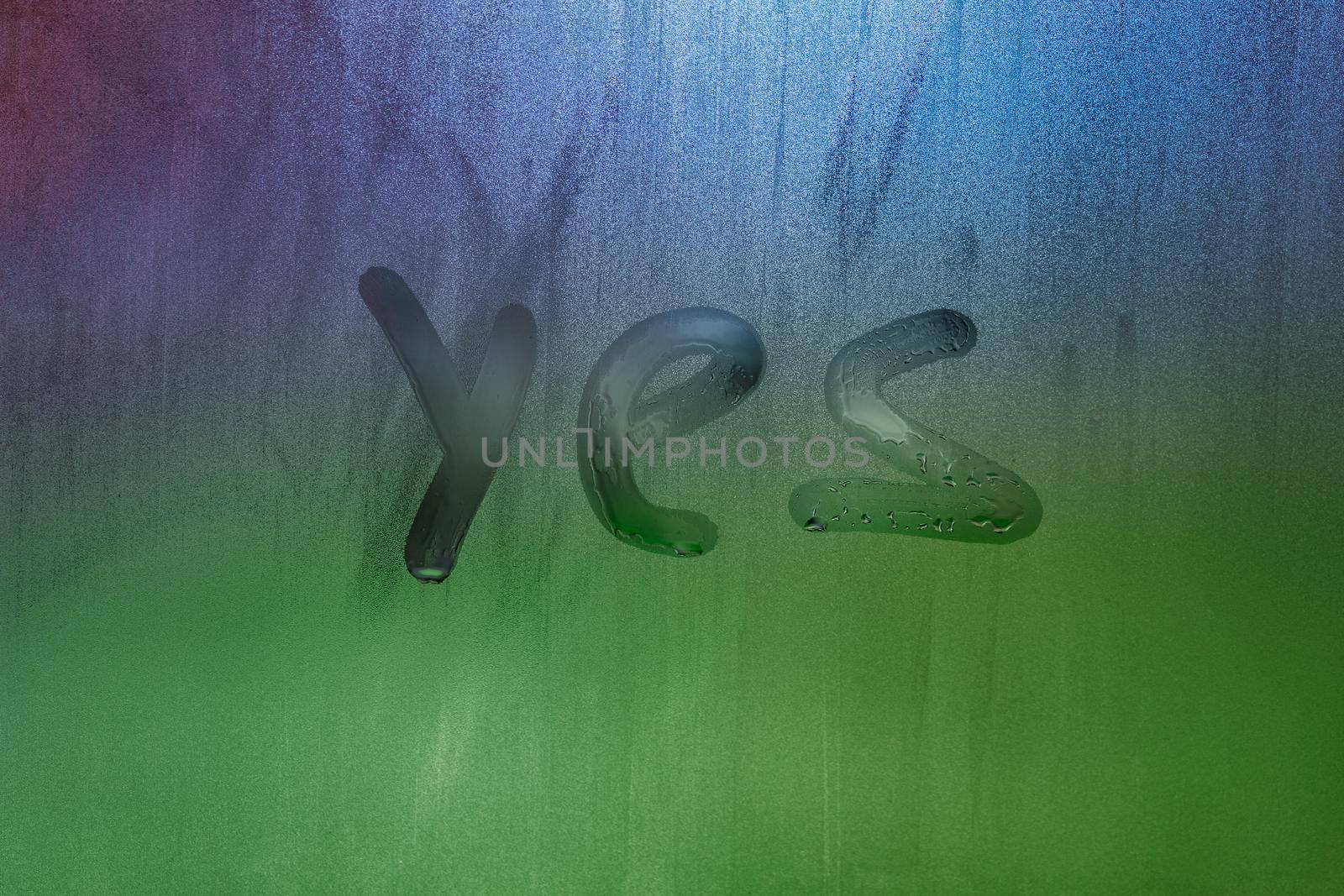 word yes handwritten on foggy window glass surface, close-up with selective focus