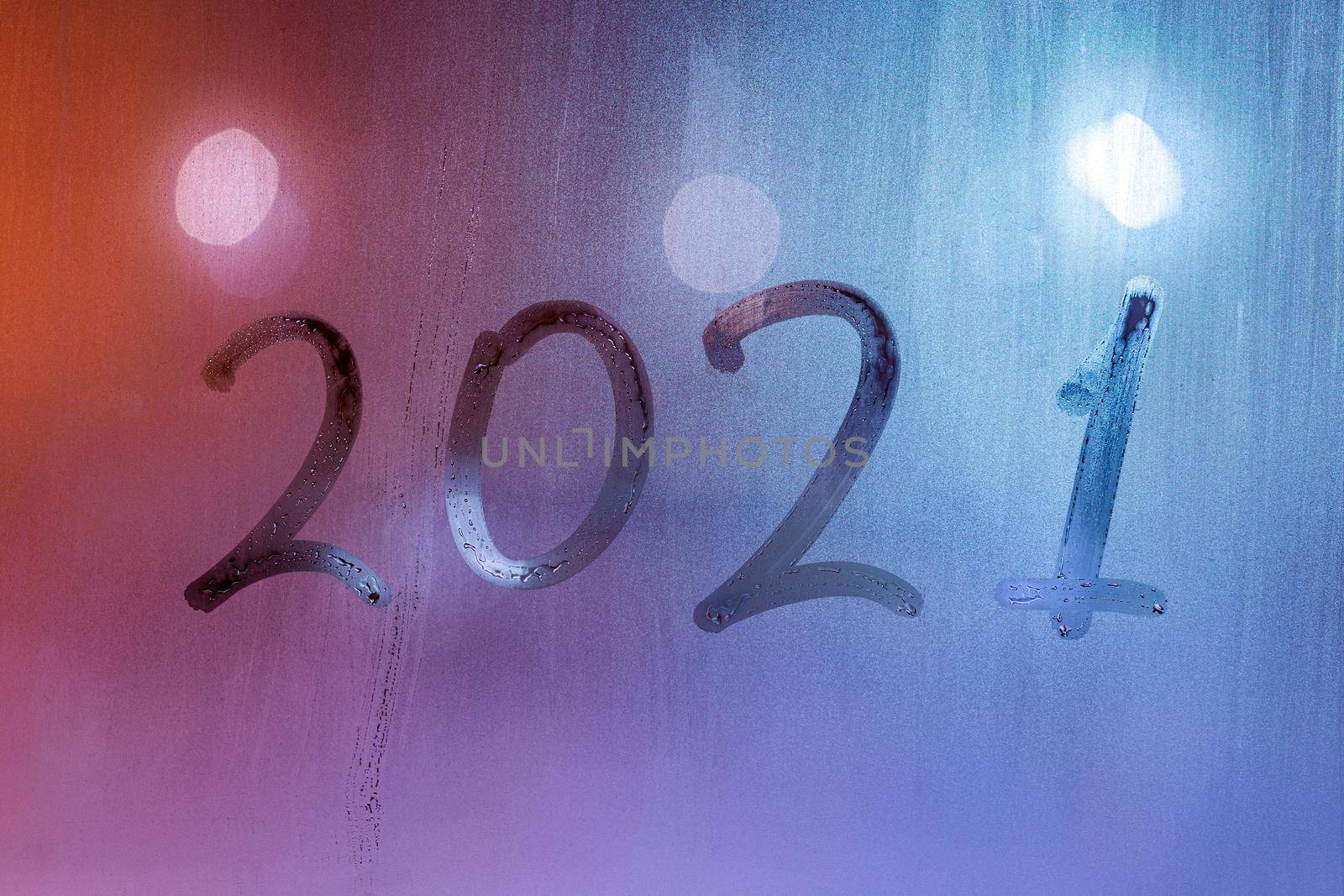 digit 2021 handwritten on wet night window glass surface, close-up with selective focus