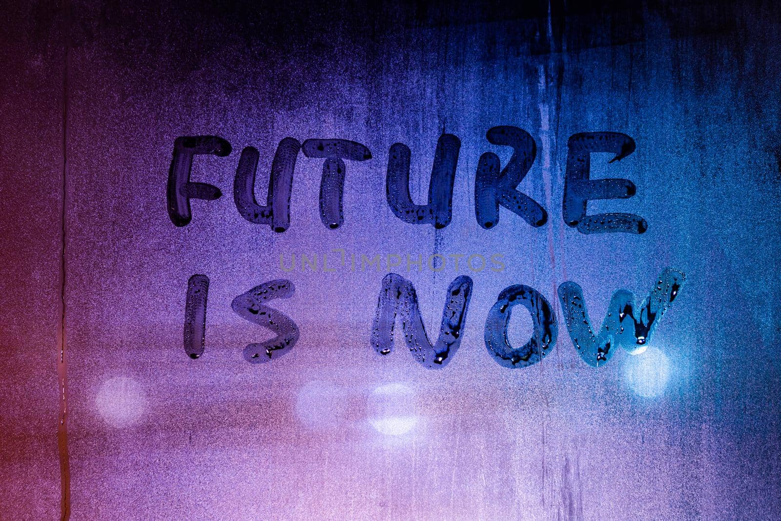 words future is now handwritten on night foggy window glass surface, close-up with selective focus