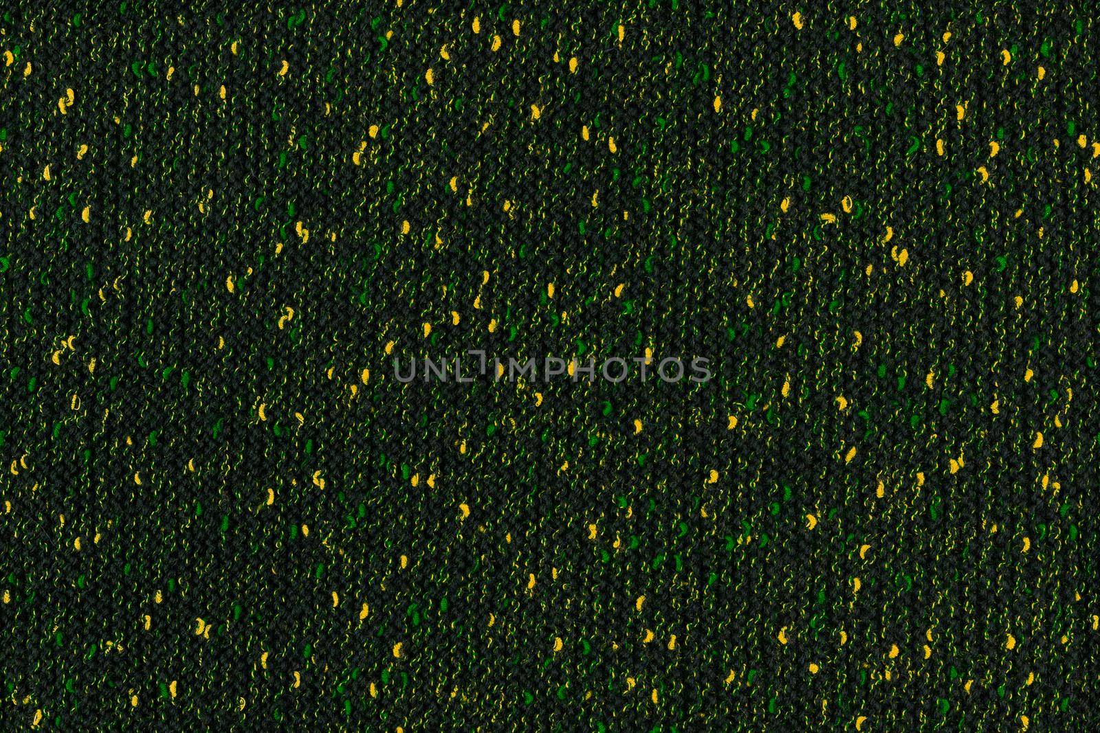 black melange manually knitted fabric with green and yellow blotches - seamless texture and flat background.