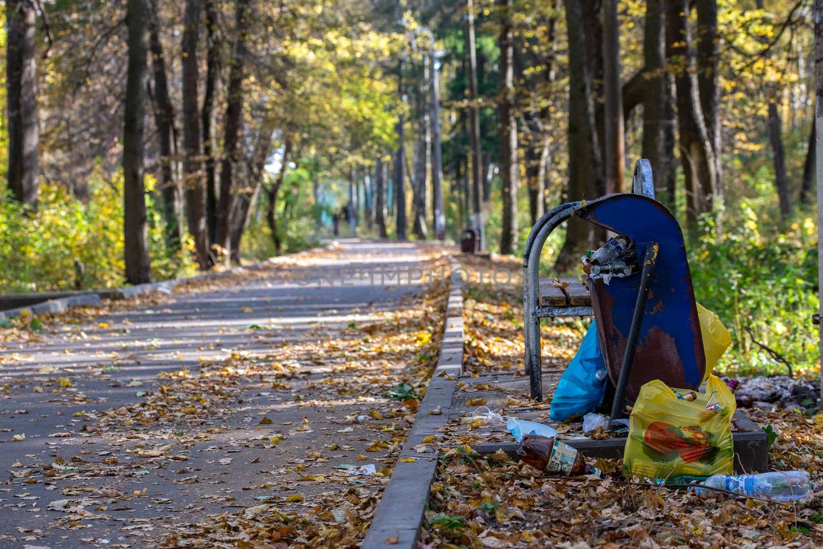 TULA, RUSSIA - OCTOBER 4, 2020: Overflowing trash can in abandoned park at daylight in early autumn.