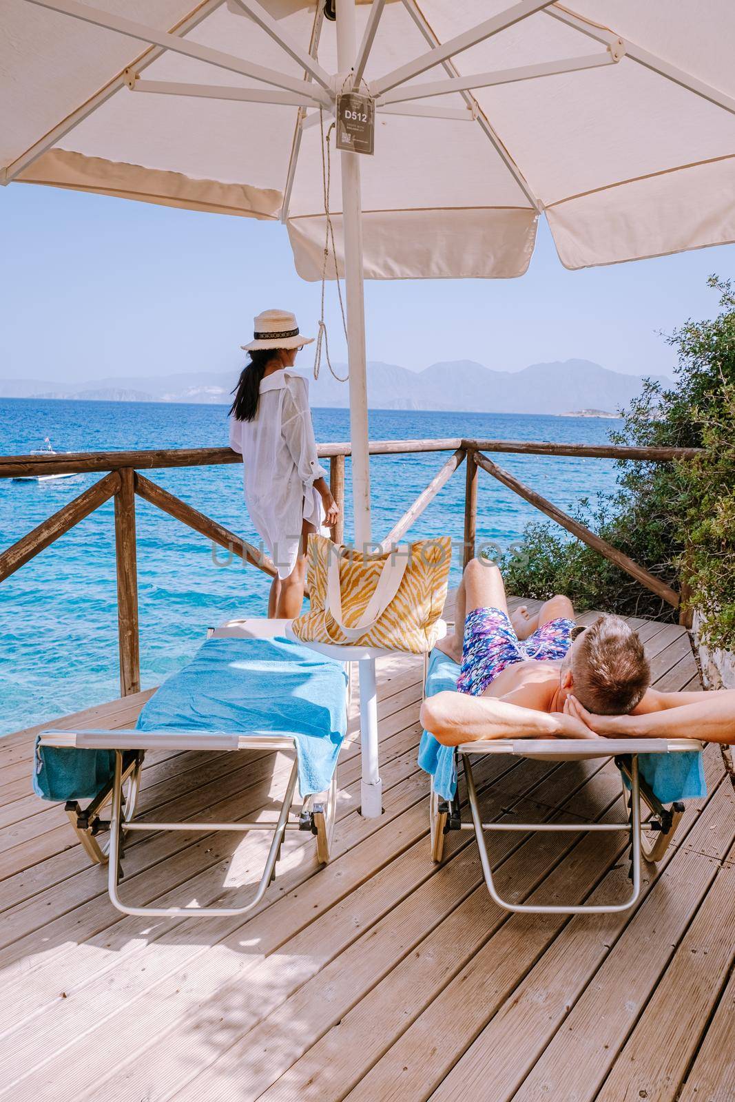 couple by the ocean on sunbed by the ocean on the beach of Crete Greece by fokkebok