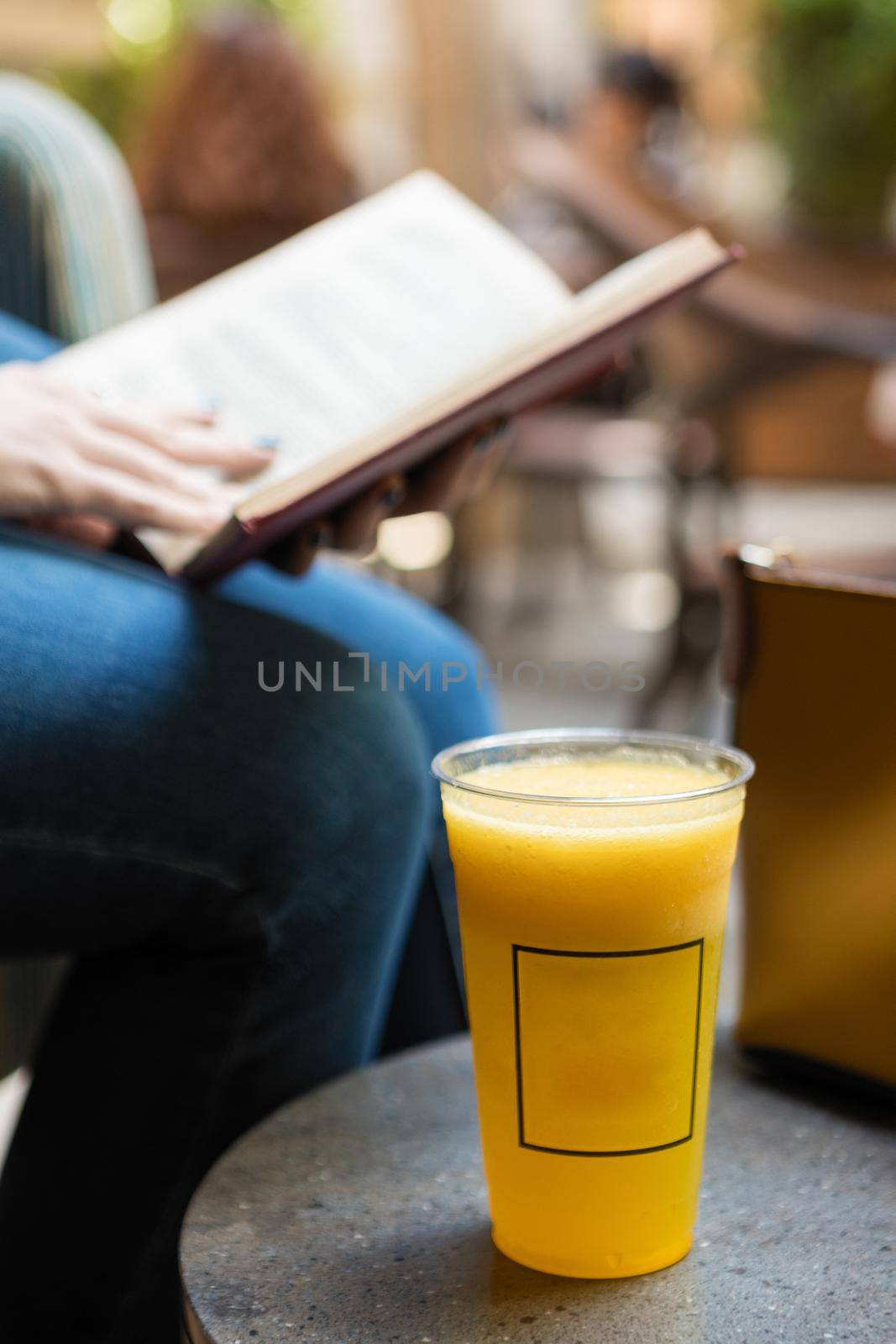 Woman reading the book with orange cocktail at cafe by ferhad