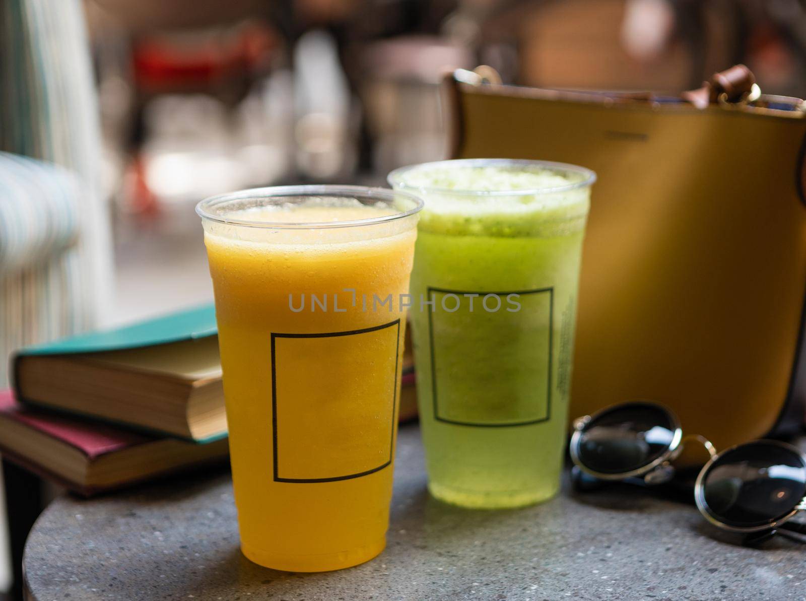 Fruit cocktails on the table with sunglass, book, woman bag