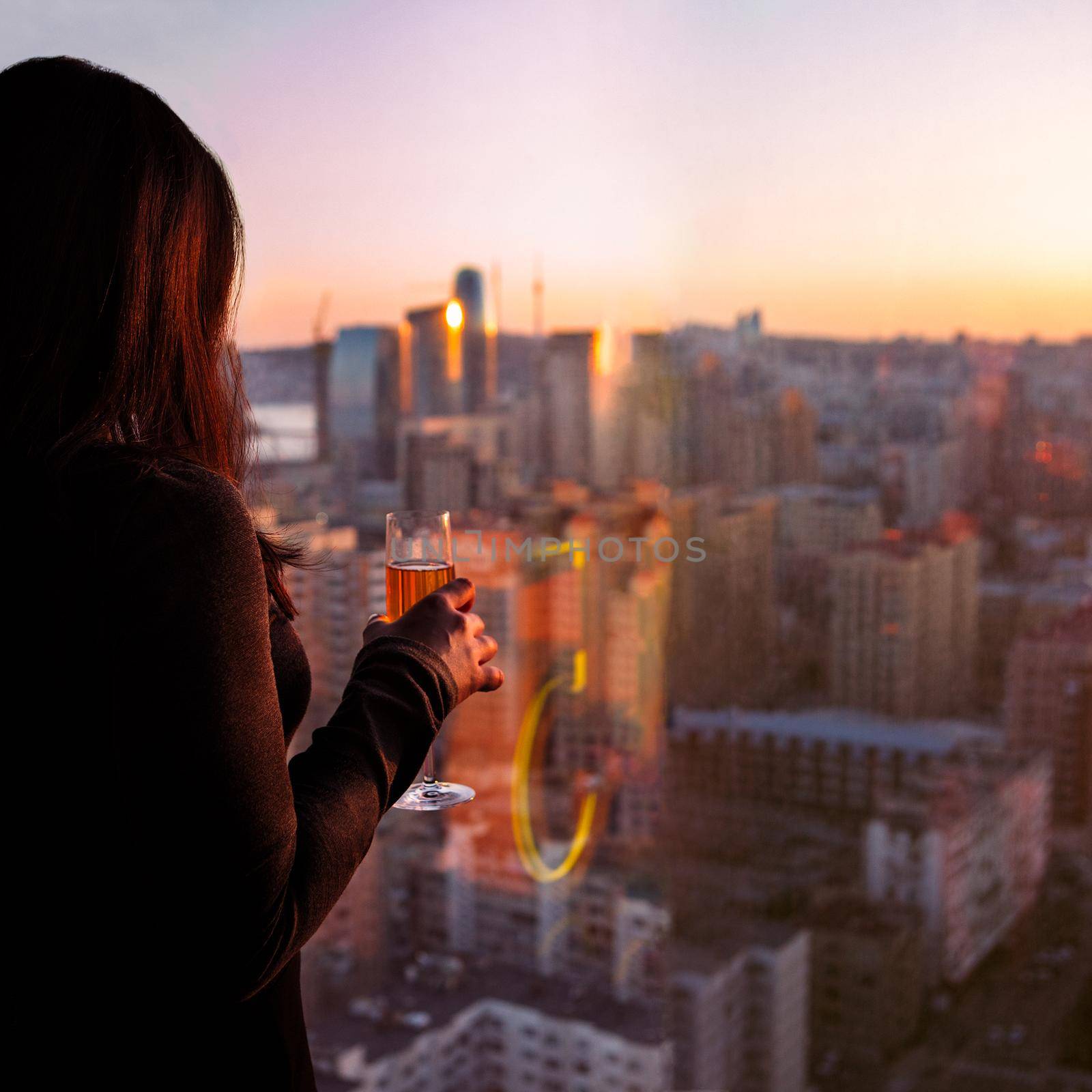 Woman holding champagne glass, looks at the city view by ferhad