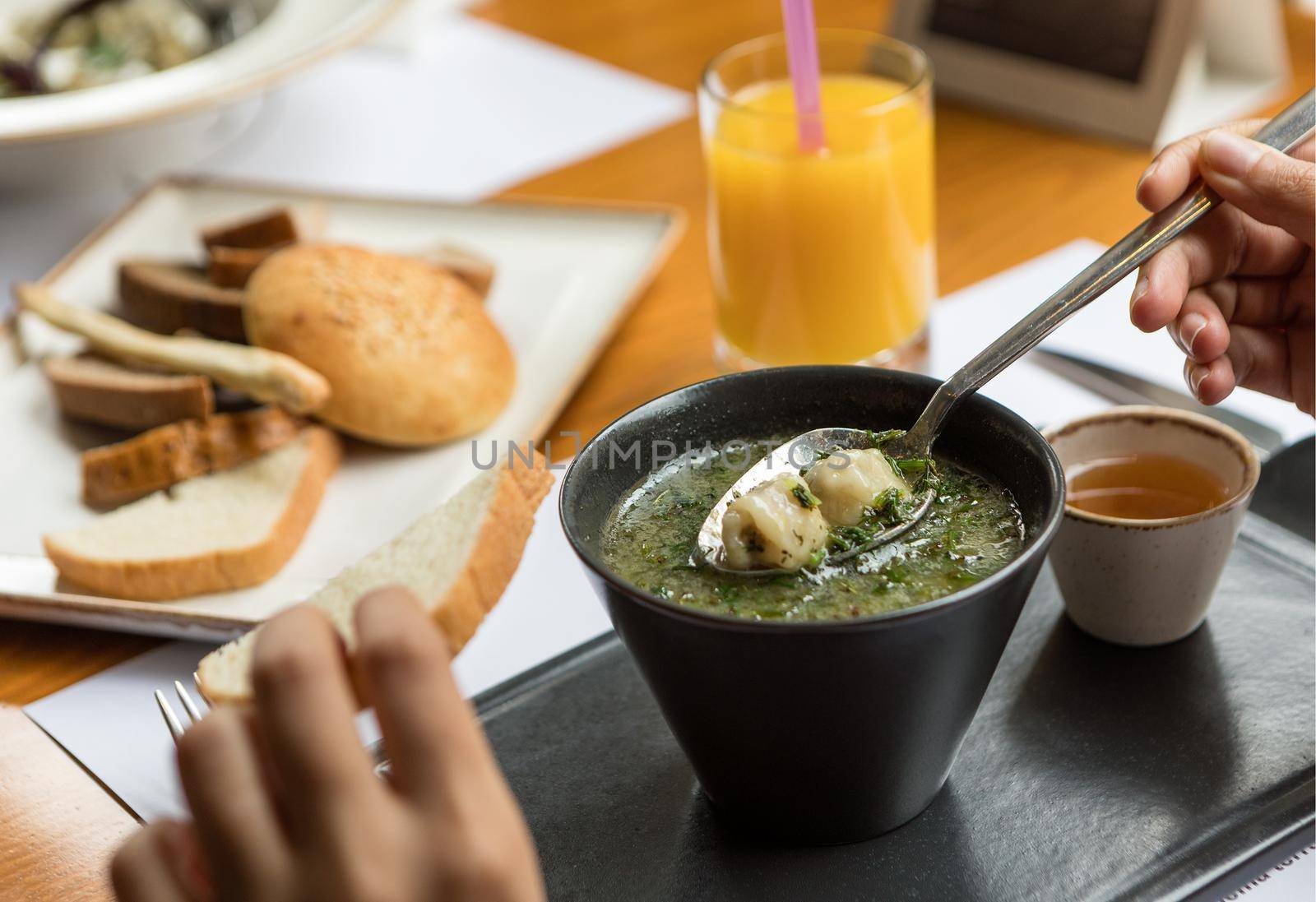 Woman eating green soup with sauce on a black plate by ferhad