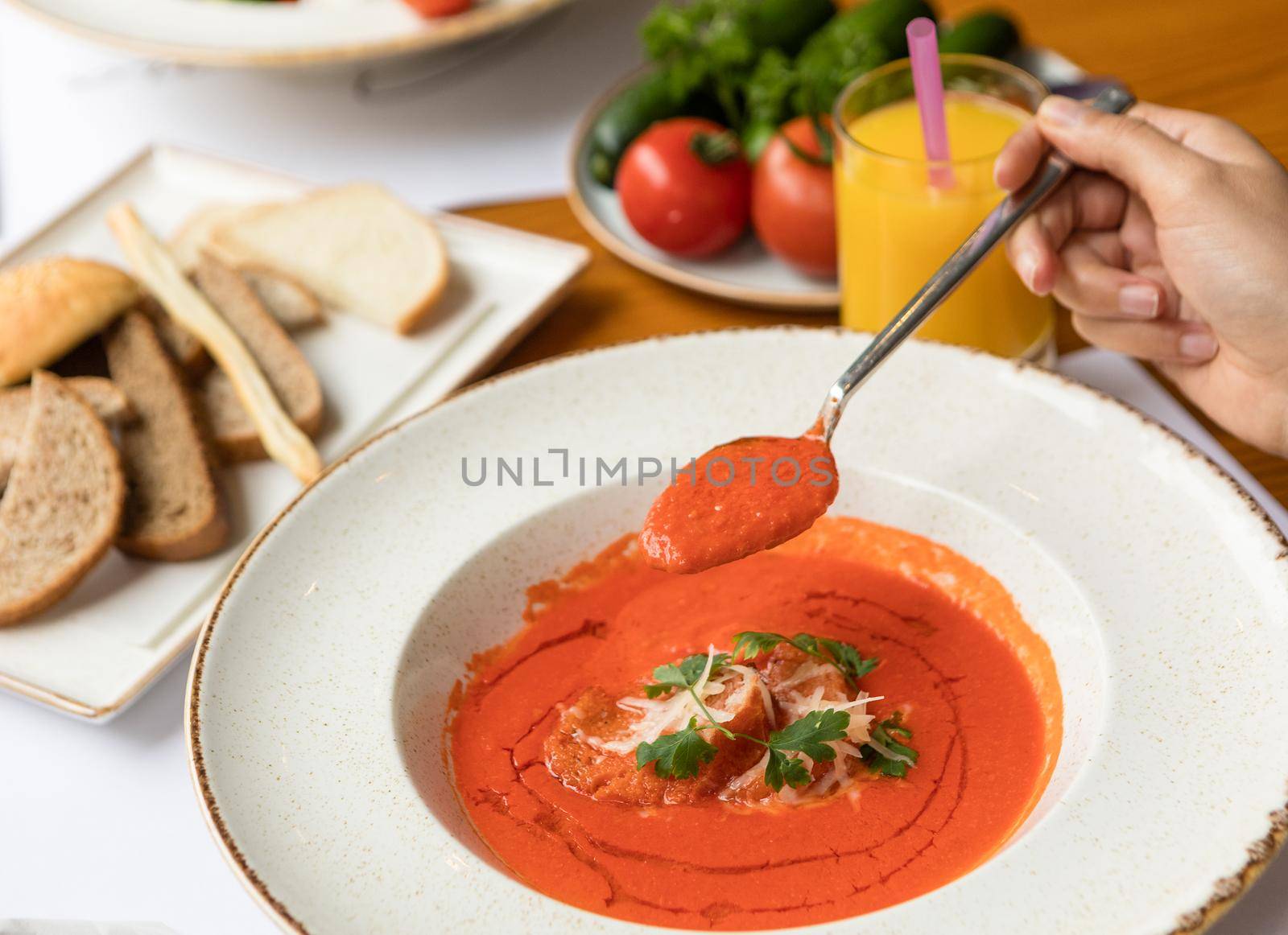 Woman eating tomato soup with sauce on a black plate
