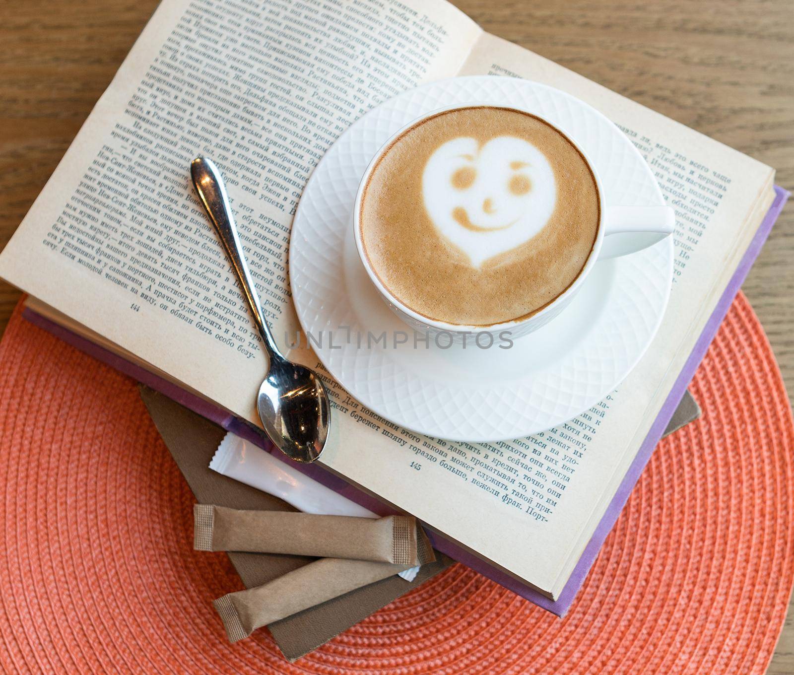 Tasty coffee cappuccino with smiling face, on a book, top view by ferhad